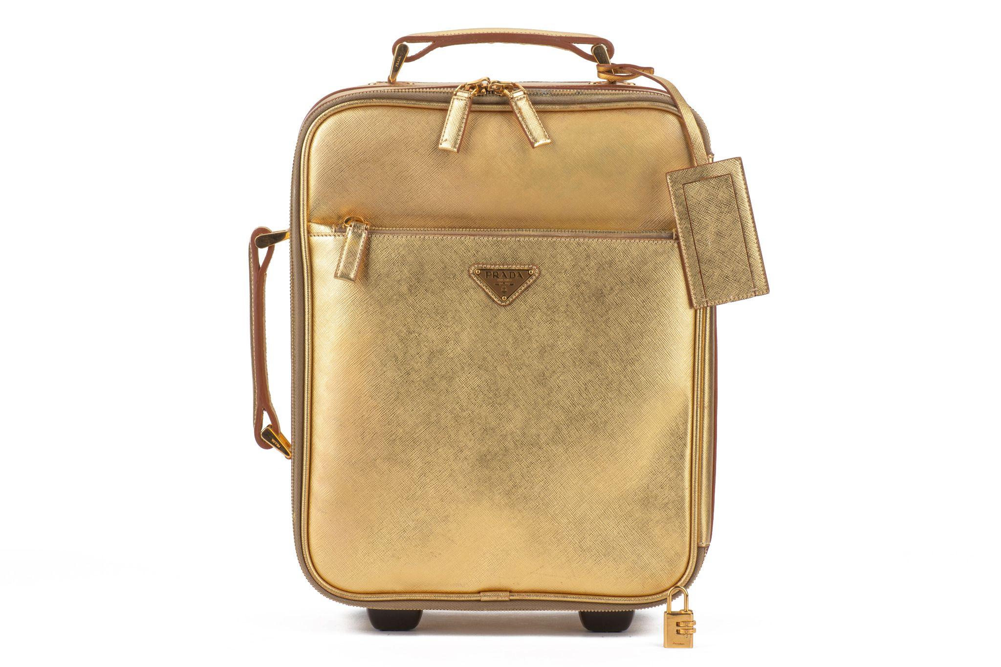 Prada super chic et rare petite valise de transport en cuir saffiano doré. Intérieur impeccable et très légères éraflures à l'intérieur. 
Serrure à combinaison, étiquette pour le nom. Couverture générique. 