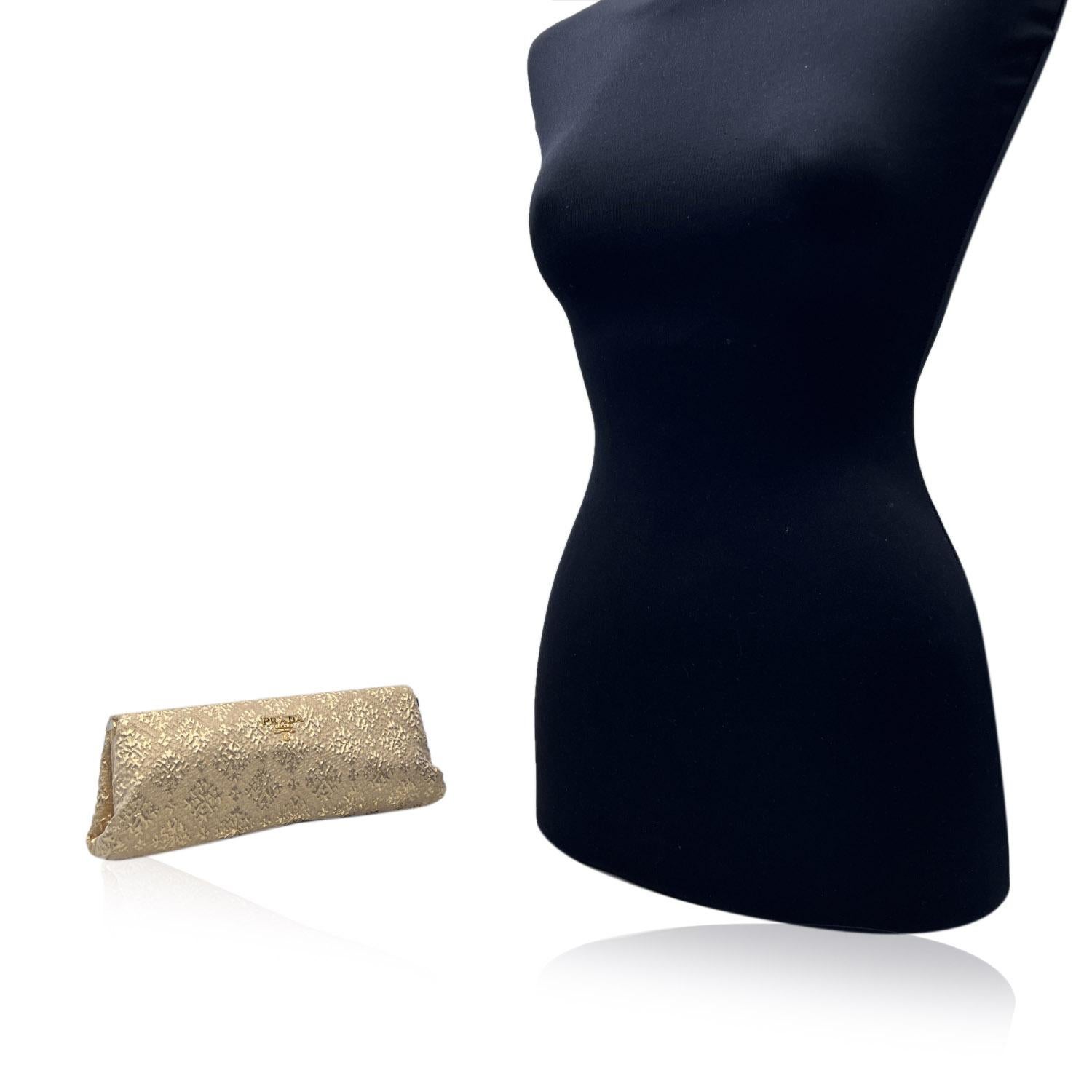 Prada goldfarbener Brokat Broccato Stoff Clutch Bag . Goldfarbene Metallbeschläge. Druckverschluss an der Seite. Prada-Schriftzug aus Goldmetall auf der Vorderseite. Satin-Futter. 1 offene Seitentasche innen. Dreieckige Prada-Logo-Lasche auf der