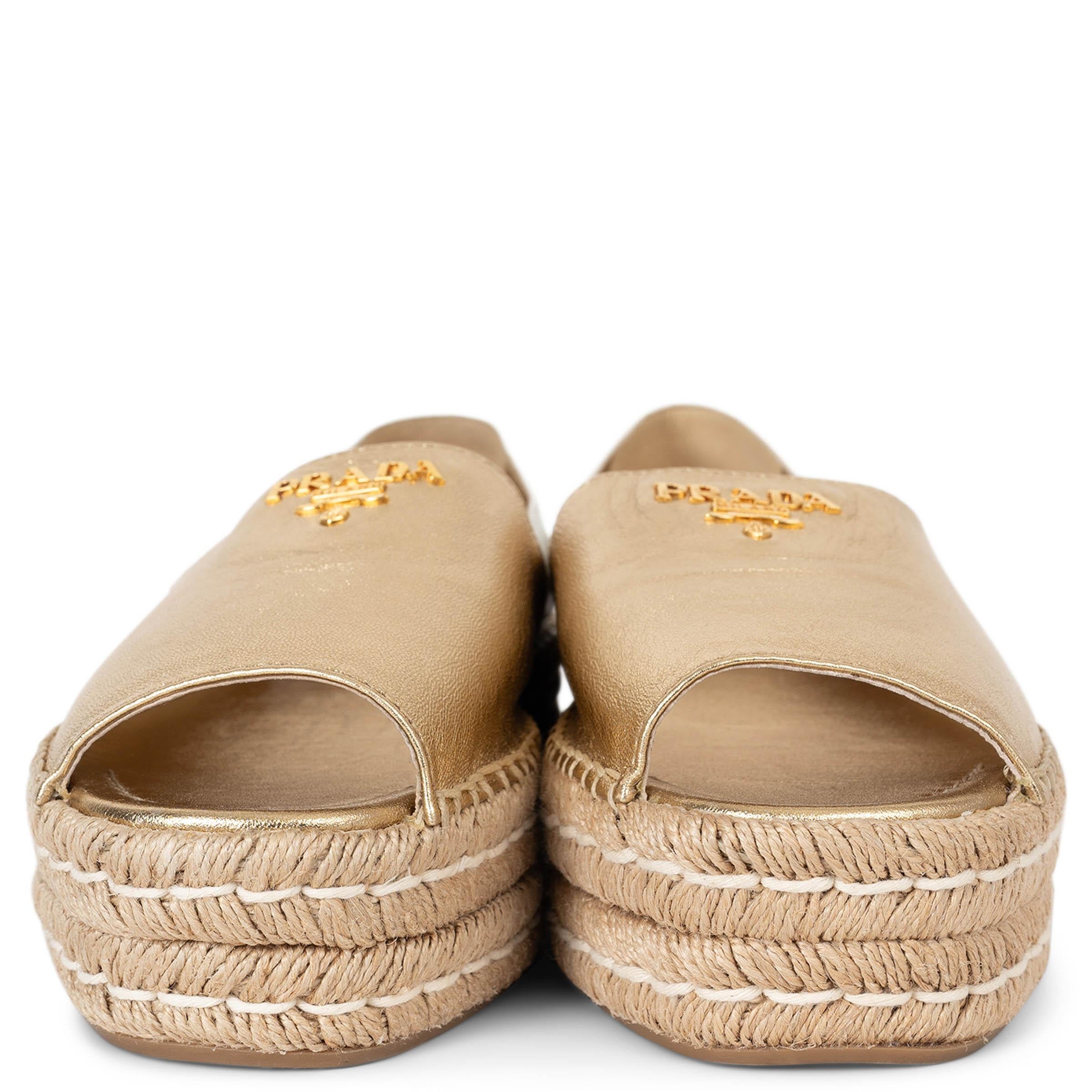 This 100% authentic Prada metallic gold and white logo embellished platform espadrille brings a touch of luxury to your casual footwear collection. Featuring a sleek metallic gold finish, it is adorned with a bold white logo and rests on a stylish