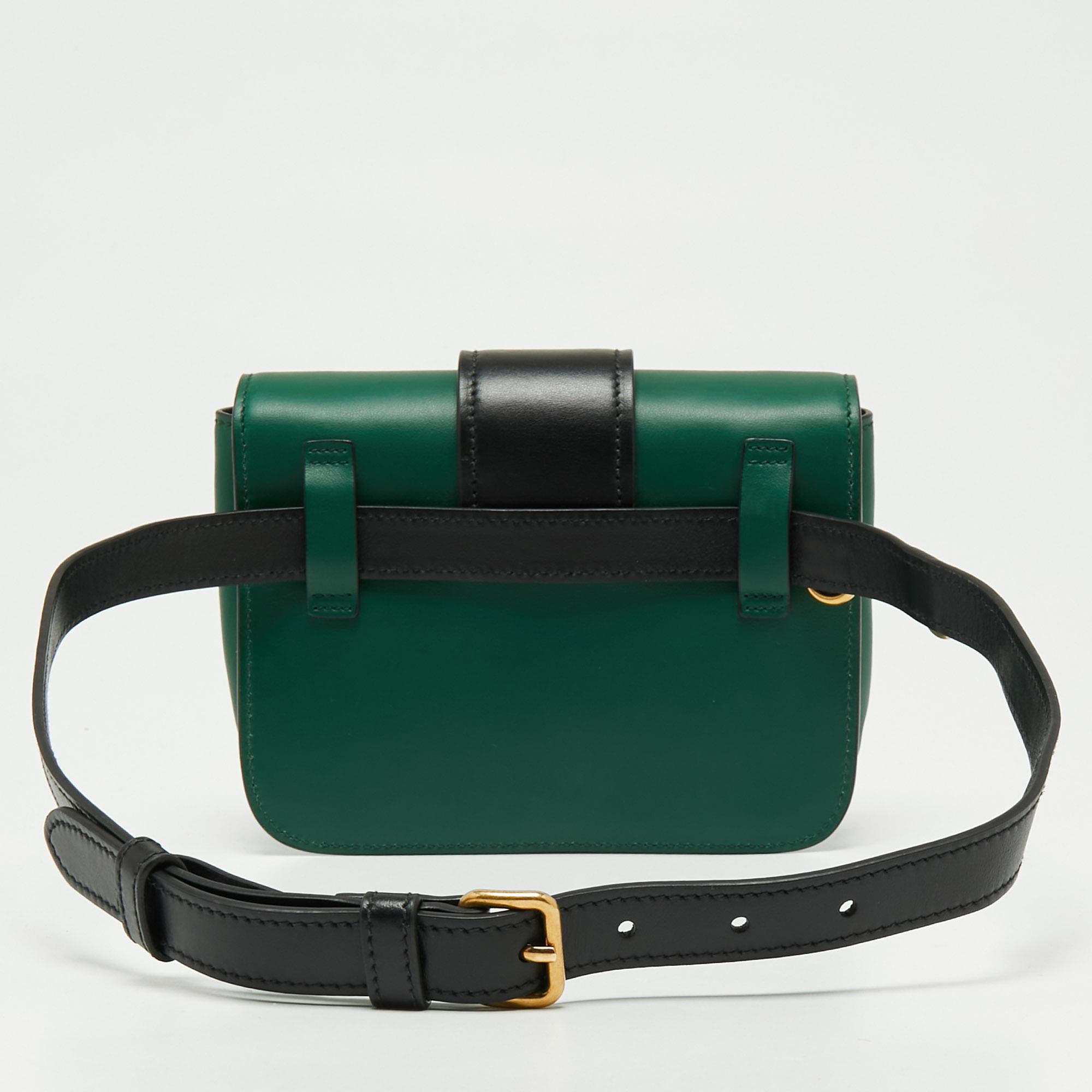 Inspired by valuable books from ancient times, the Cahier by Prada is a best-seller. This belt bag is crafted in Italy using green and black leather. The band-detailed flap with the brand logo opens to a compact interior and the waist belt strap