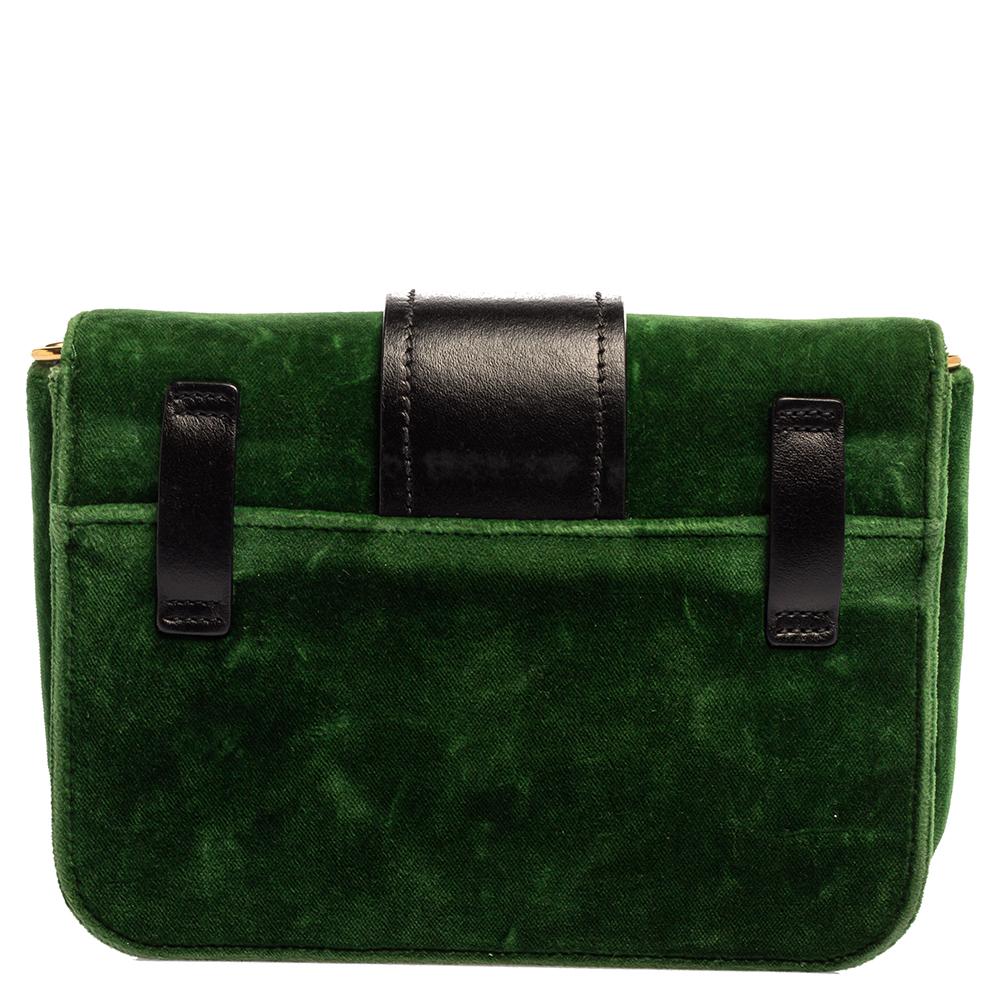 Inspired by valuable books from ancient times, the Cahier by Prada is a best-seller. This shoulder bag is crafted in Italy with green velvet and black leather. It features a gold-tone tuck-in loop at the front that adds a touch of contrast. The