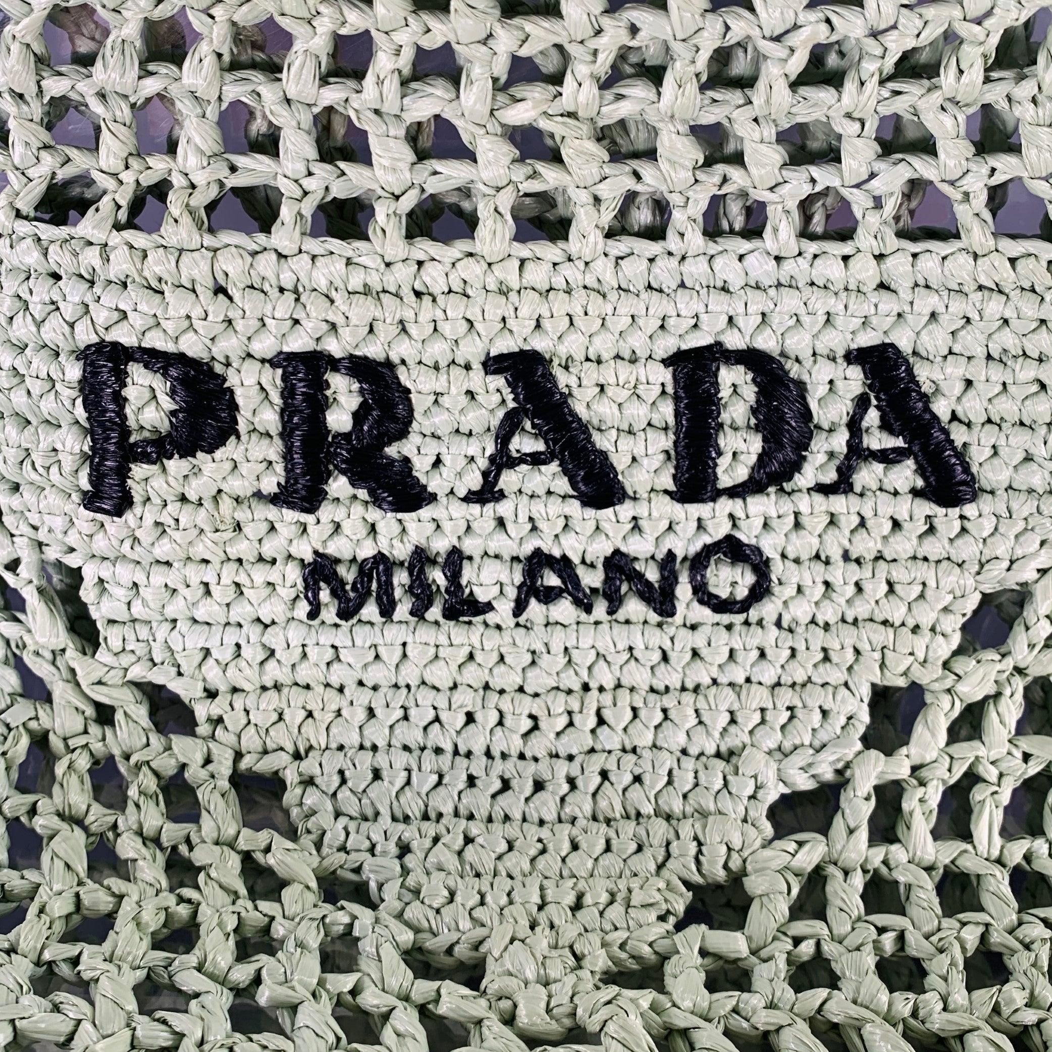 PRADA handbag
in a mint green raffia featuring a crochet woven design with black PRADA logo, and tote bag style. Made in Italy.Very Good Pre-Owned Condition. 

Measurements: 
  Length: 14 inches Width: 1.25 inches Height: 14 inches Drop: 10 inches 
