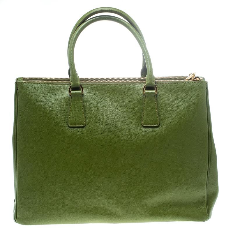 Beautifully crafted from Saffiano Lux leather, this Prada tote is a creation you can't miss. It has a classy green exterior along with two zippers and a spacious nylon interior that will hold your necessities. The bag is held by two handles, and