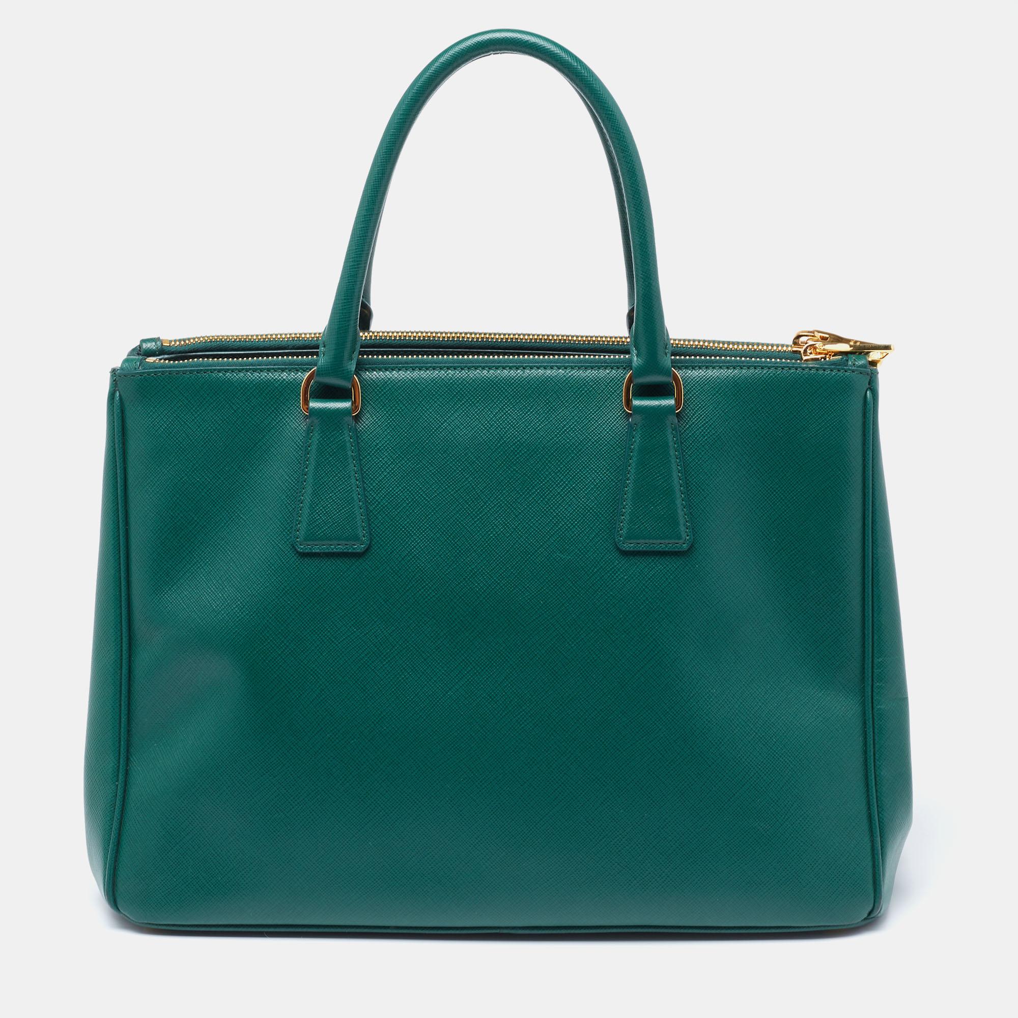 Feminine in shape and grand in design, this double zip tote by Prada will be a loved addition to your closet. It has been crafted from leather and styled minimally with gold-tone hardware. It comes with dual top handles, two zip compartments, and a