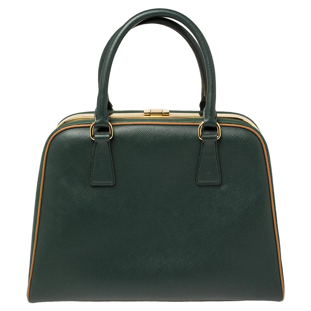 High in appeal and style, this satchel is a Prada creation. It has been crafted from Saffiano lux leather and shaped to exude class and luxury. The bag is designed with a gold-tone clasp on the top metal frame and comes with two handles and a