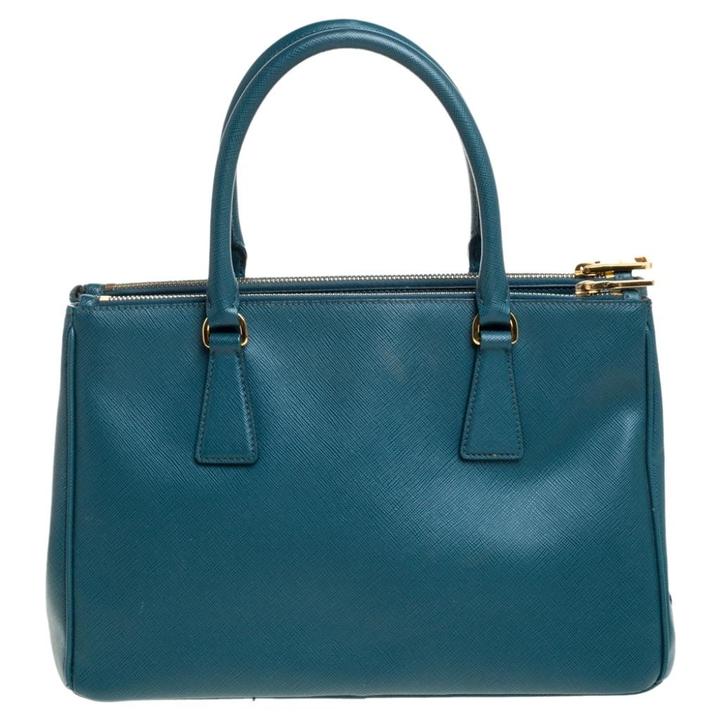 High on style and class, this Galleria Double Zip tote by Prada will be a cherished addition to your closet. It has been crafted from Saffiano Lux leather in a green shade and styled minimally with gold-tone hardware. It comes with dual handles and