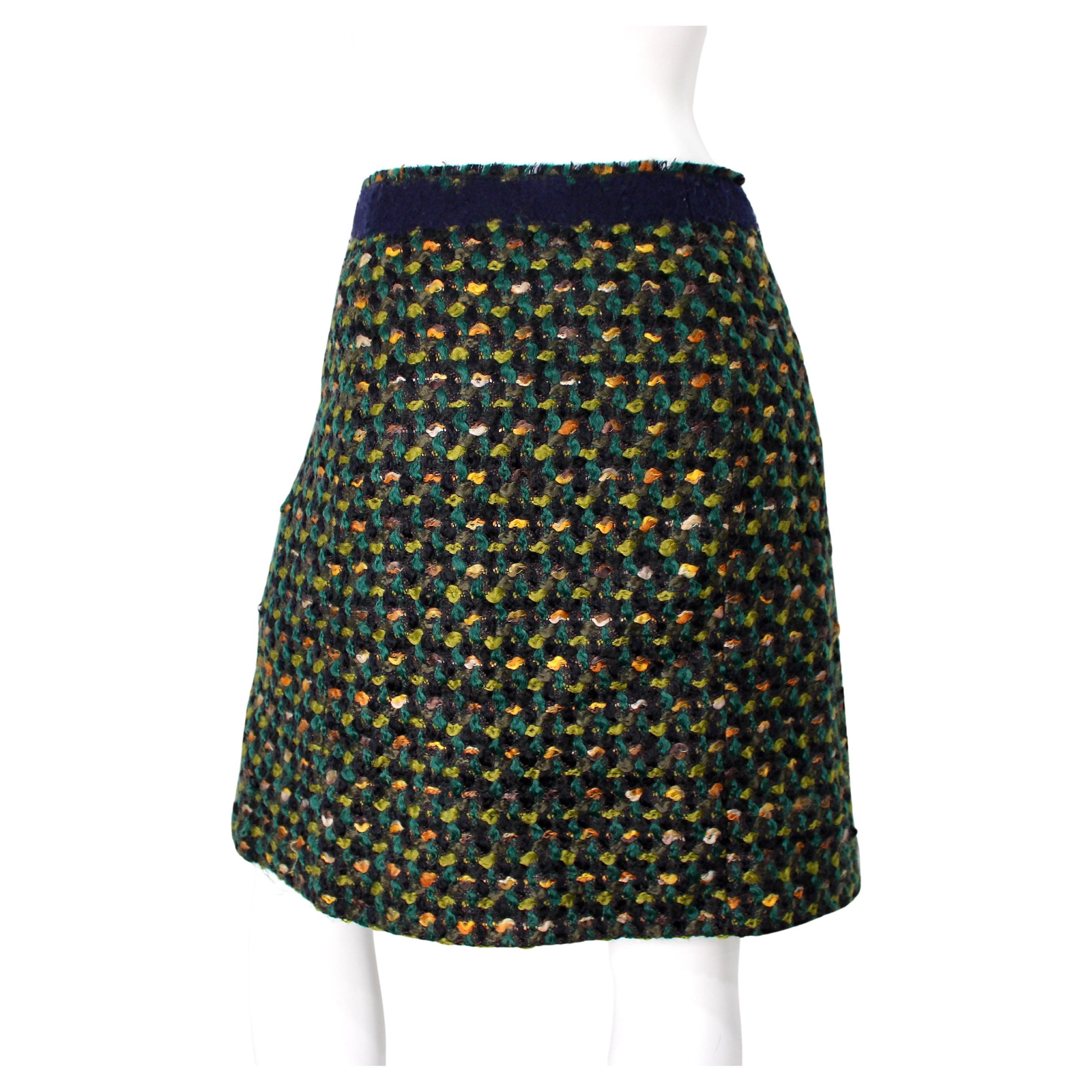 La jupe en tweed de laine verte Prada, datant d'environ 2010, incarne l'élégance intemporelle et le style sophistiqué. Confectionné en tweed de laine de haute qualité, il arbore une riche teinte vert foncé qui ajoute une touche de luxe et de