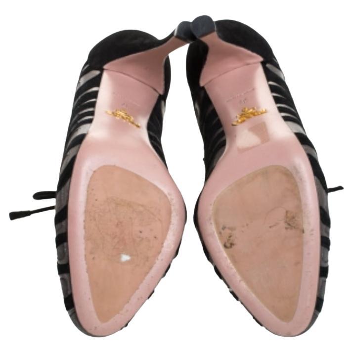 Prada eleva tu cociente de estilo dándote la atención justa con este precioso par de botines. Estos botines de ante y piel tienen cordones en las lengüetas, un interesante diseño de llamas en toda la caña y tacones altos. Añade un toque de dinamismo