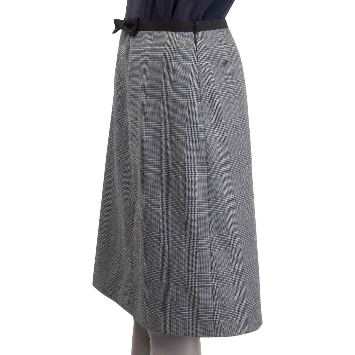 100% authentic Prada houndstooth plaid knee-length skirt in gray and black wool (100%). Embellished with a black bow on the front side. Opens with a concealed zipper and a hook on the side. Lined in black viscose (67%) and silk (33%). Has been worn