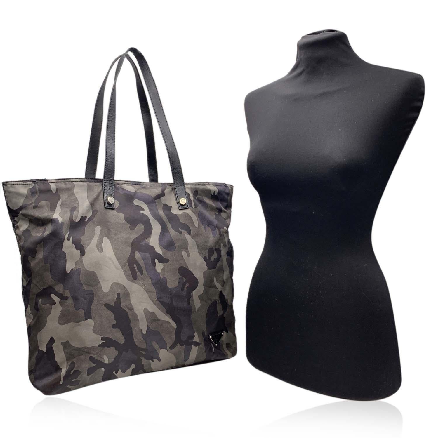 Prada Unisex tote bag in grey camouflage nylon canvas, mod. VA0883. Silver metal hardware. Upper zipper closure. Fabric lining with Prada signatures. Prada triangle logo on the side. 1 side zip pocket and 2 side open pockets inside. Double top