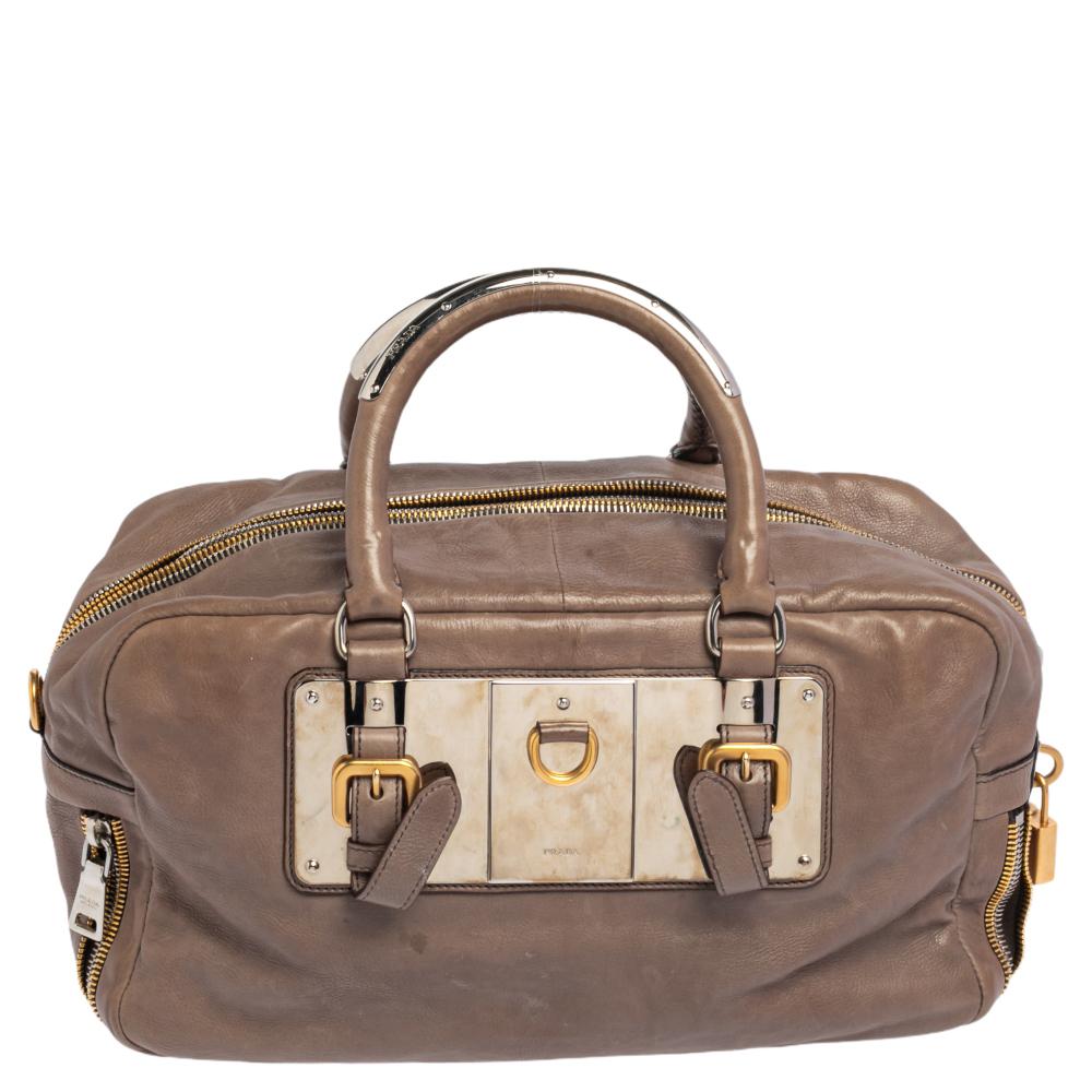 Diese elegante Bauletto-Tasche von Prada ist aus Leder gefertigt und eignet sich perfekt für Ihre modischen Unternehmungen. Die Tasche besticht durch ihre graue Farbe, die sie bedeckt, zwei runde Henkel, einen Metallverschluss auf der Vorderseite