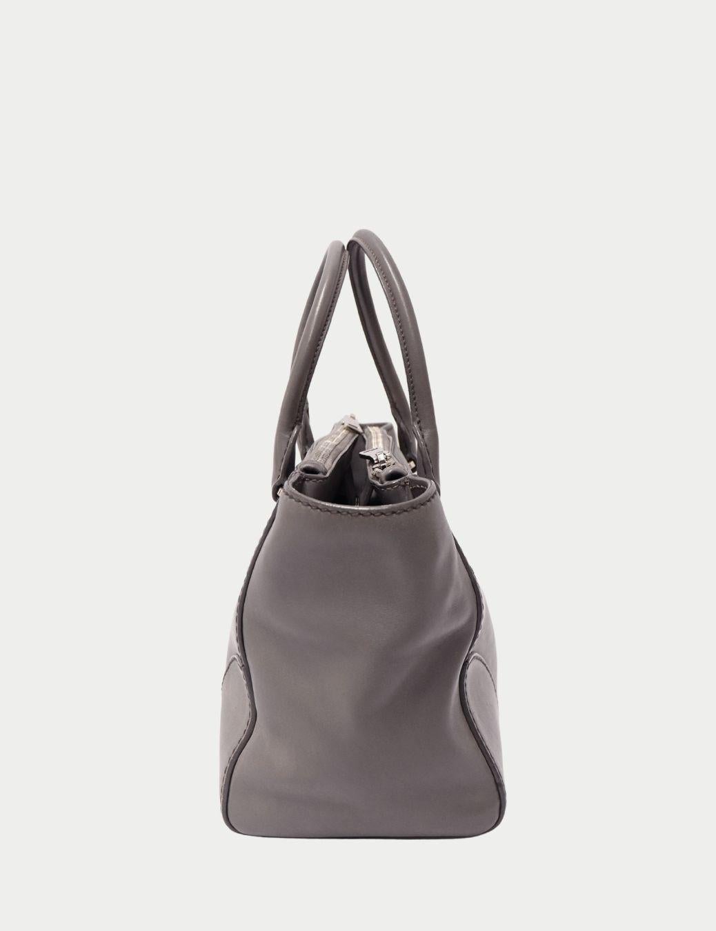 Borsa Prada in pelle grigia con manici superiori e placca logo in argento

L'eleganza sobria incontra l'artigianato senza tempo in questa borsa in pelle grigia di Prada, un pezzo sofisticato pensato per la donna moderna. Realizzata in pelle liscia,