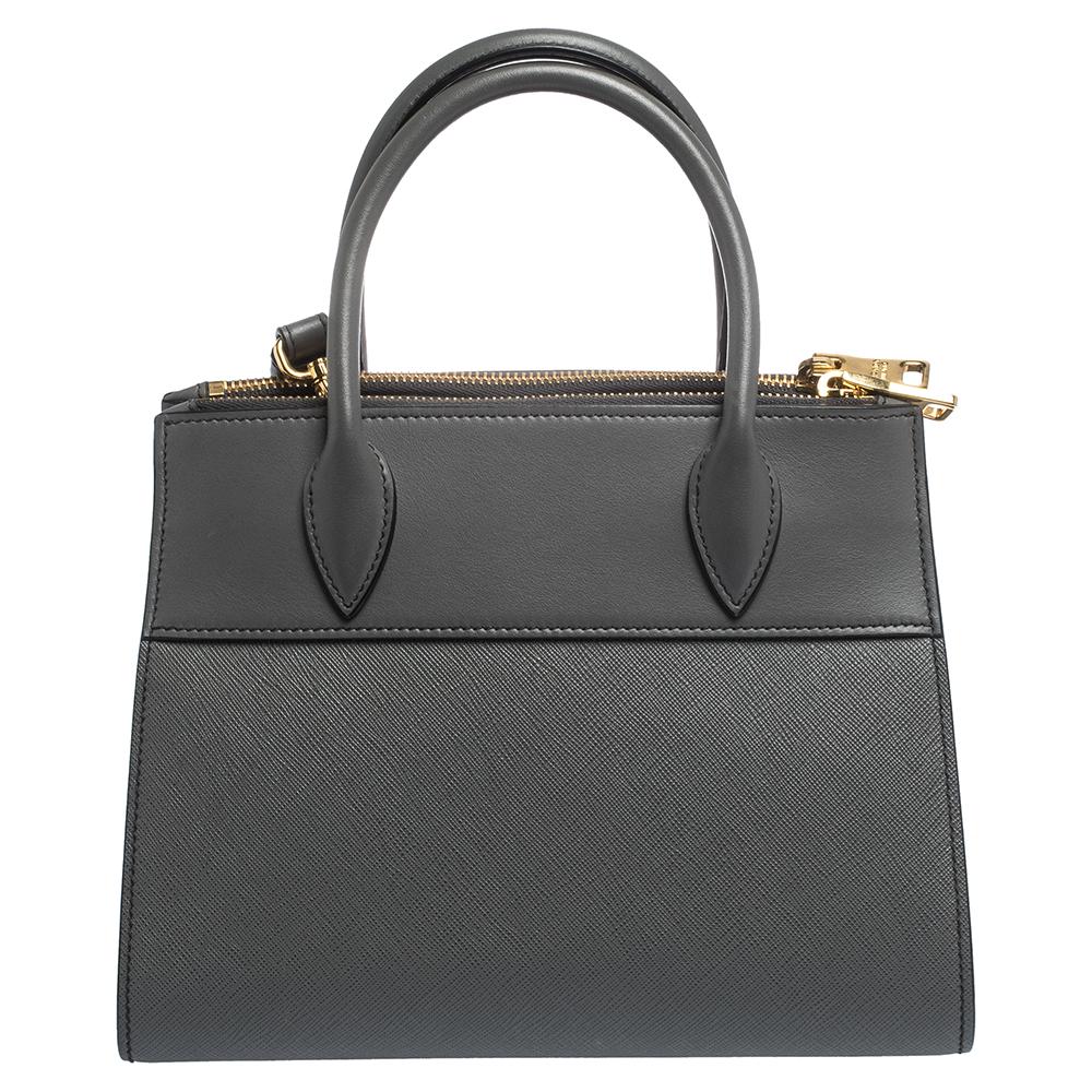 Prada's Paradigme tote exudes appeal through a structured shape and minimal detailing. Crafted from leather, the tote in grey has two handles, a shoulder strap, triangular side gussets and a spacious interior. Make it yours today!

Includes: