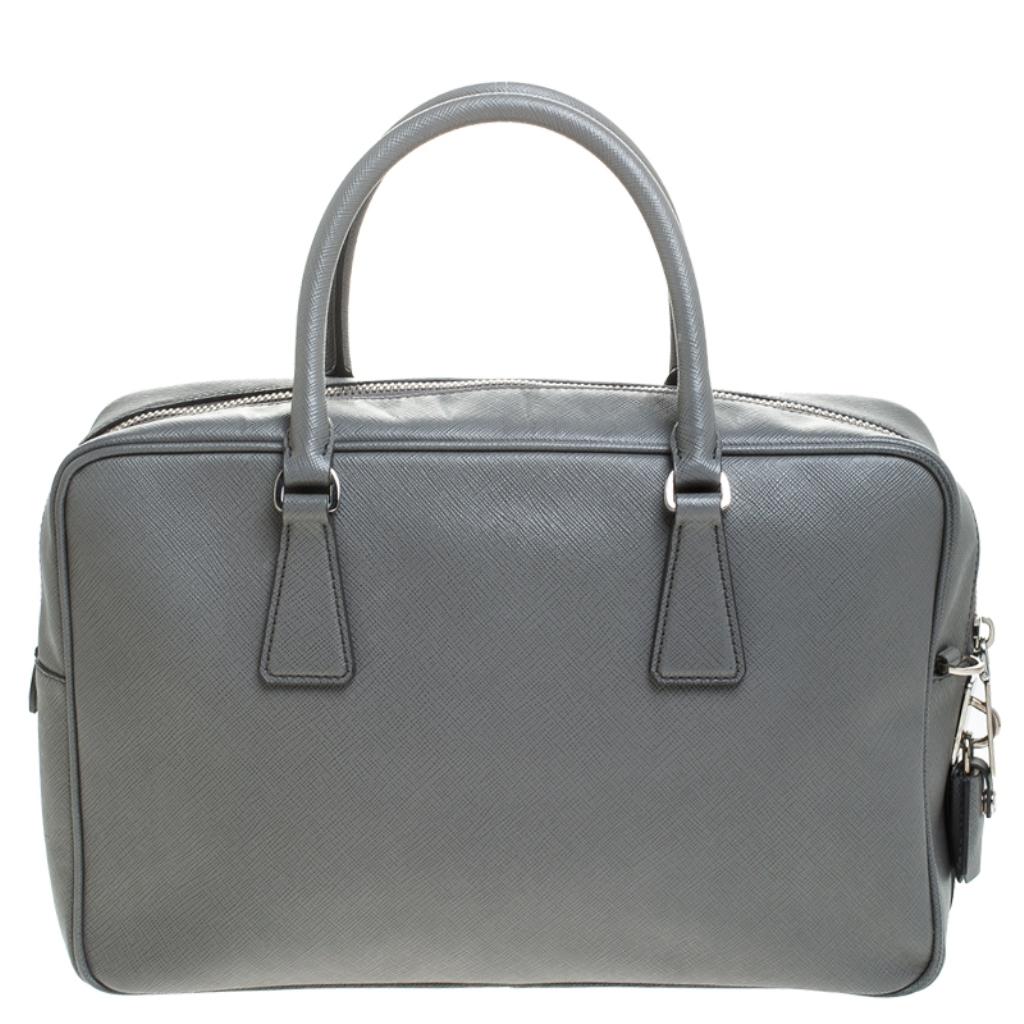 Crafted from grey Saffiano leather, this handbag features Prada's iconic logo, top zip closure and silver-tone hardware. This bag is accentuated with dual top handles along with a detachable and adjustable shoulder strap and leather clochette to the