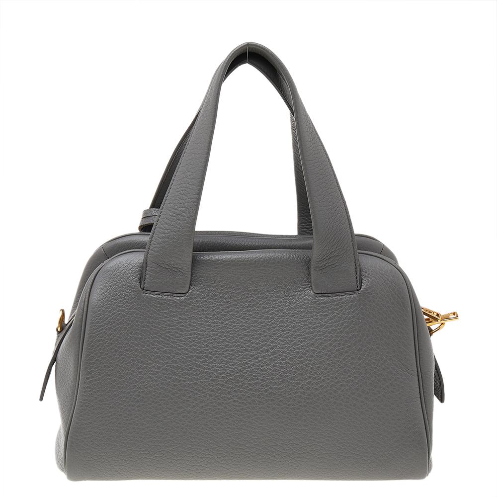The lovely shoulder bag by Prada is classic in appeal and has a functional design. This beauty in grey is crafted from leather and is equipped with two top handles, the brand logo at the front, and a leather clochette. The nylon-lined interior is
