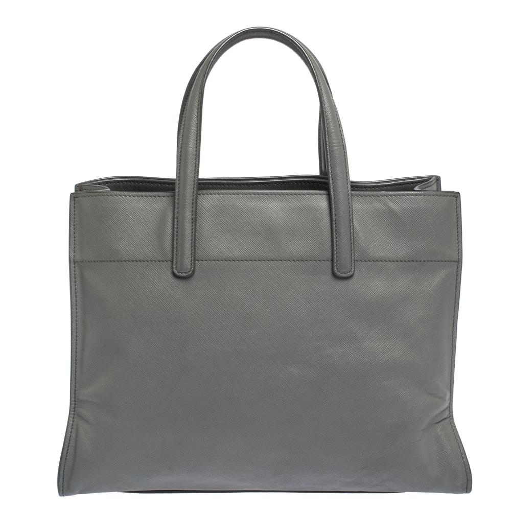 This lovely tote from Prada is crafted from Saffiano Lux leather and features a grey shade. It flaunts dual handles, brand logo, protective metal feet, and a spacious leather-lined interior with enough space to house all your belongings. It is