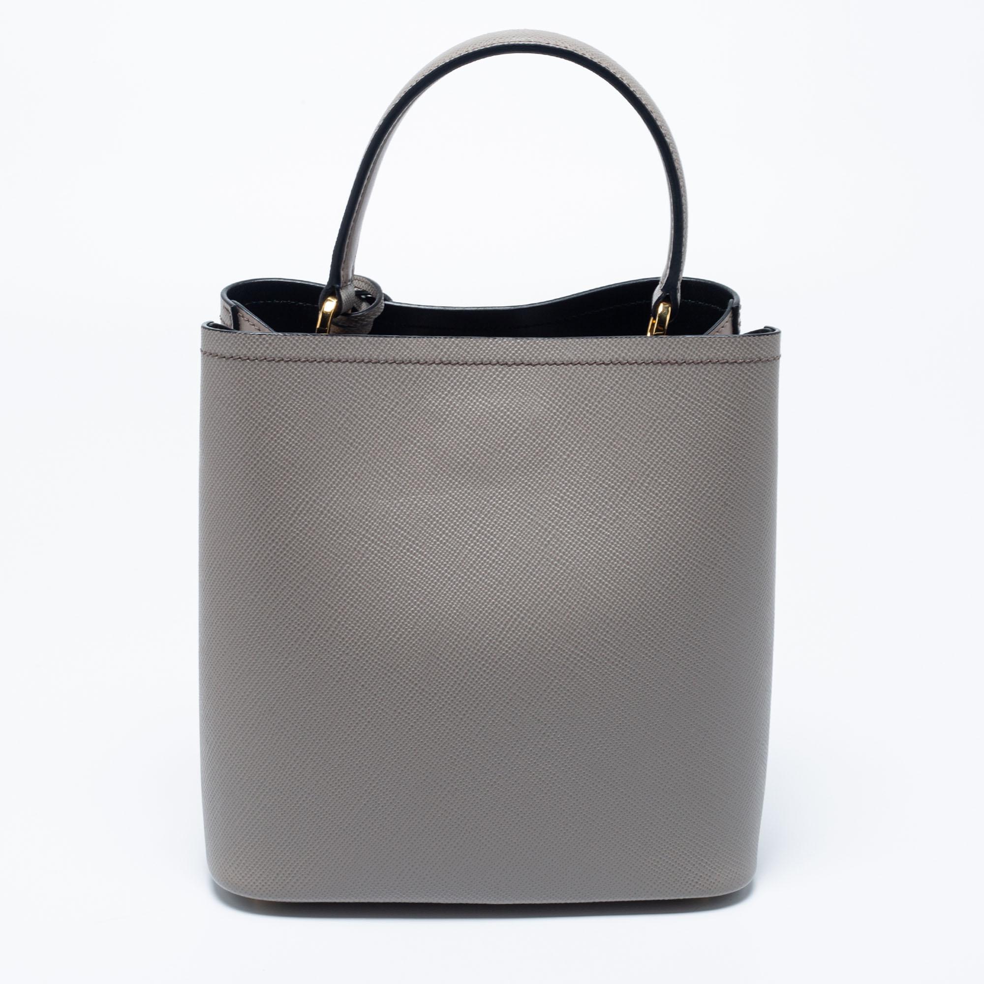 Distinctive in design, the Panier bag from Prada definitely deserves to be yours! This one has been crafted from grey Saffiano Lux leather and features a single top handle, a shoulder strap, and the brand logo on the front. It opens to a spacious