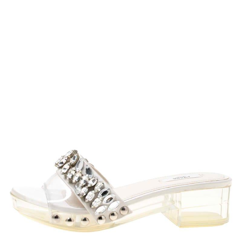 Etheral and charming, these slides from Prada is directed to impart an opulent appeal to your evening looks. It has a broad PVC strap on the front accented with crystal-embellished satin trims. The pair is styled with comfortable leather and satin