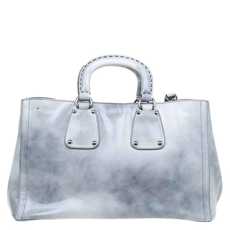 Crafted with glazed calfskin leather, this Prada shopping tote has silver tone details, top handles and an adjustable/removable shoulder strap. It has a spacious interior with a zipped pocket to hold all your essentials. Four protective feet have