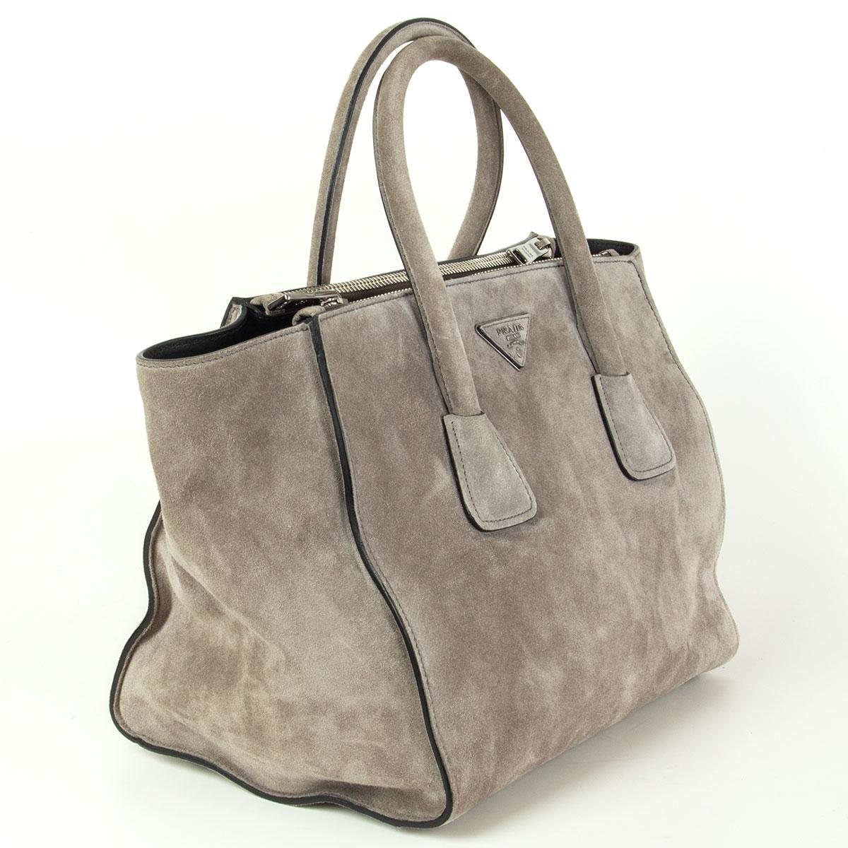 Prada Twin Pocket tote in grey suede featuring silver-tone hardware. Opens with a push-button and is lined in smooth black lambskin with two extra large zip pockets on the side, a small zip pocket against the back and a open pocket against the