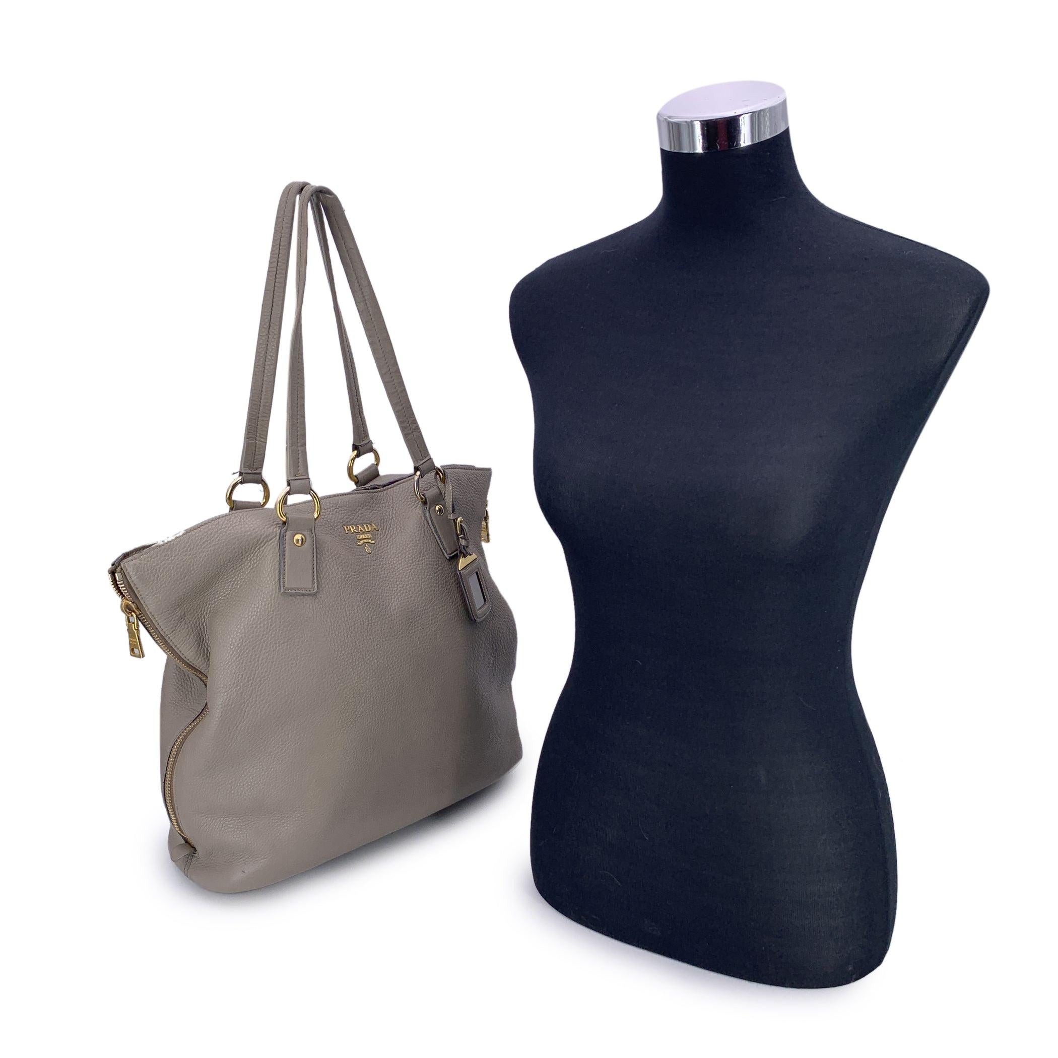 Ce magnifique objet est accompagné d'un certificat d'authenticité fourni par Entrupy. Le certificat sera fourni sans frais supplémentaires Élevez votre quotidien avec ce magnifique sac fourre-tout PRADA, fabriqué en luxueux cuir texturé gris taupe -