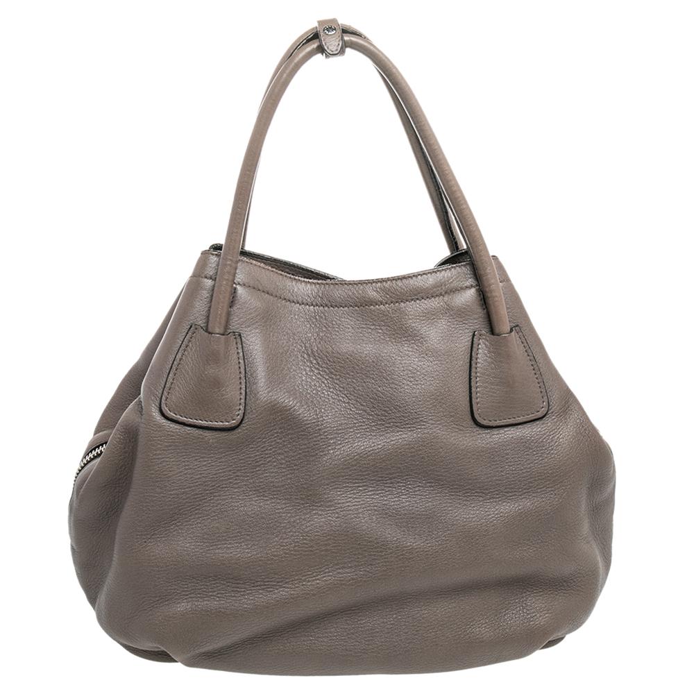 This beautifully stitched tote in Vitello Daino leather is by Prada. With a capacious leather-lined interior, it will house more than your essentials. Boasting two handles and a fine finish, this grey tote offers style and everyday ease.

Includes: