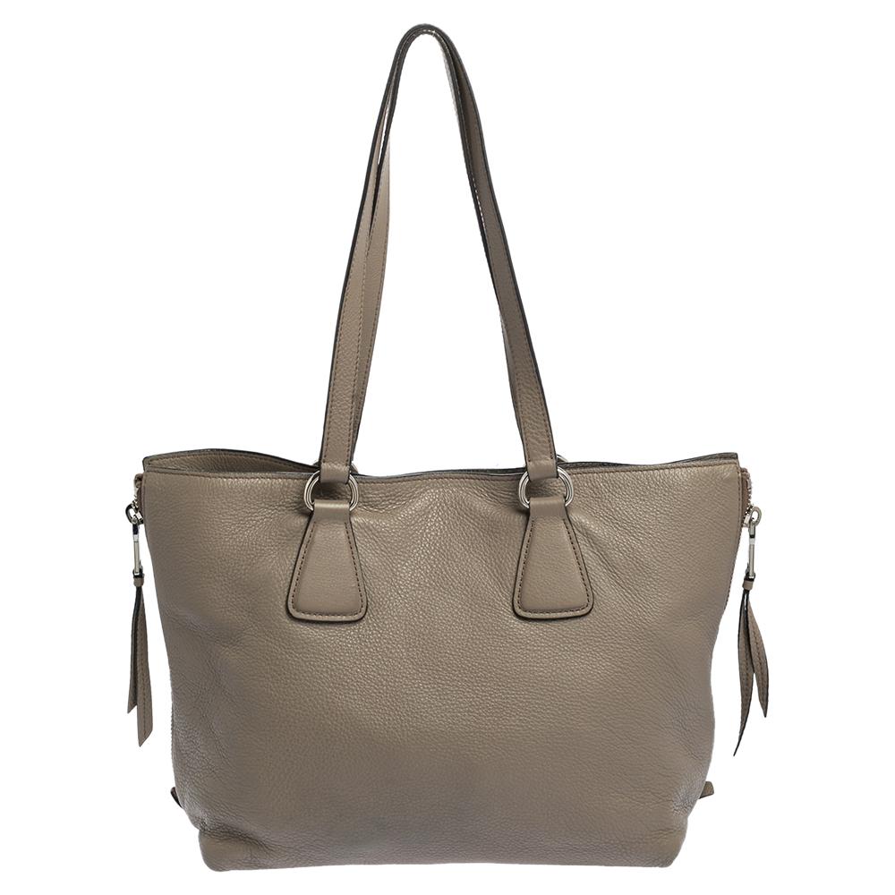This Prada creation will fetch you admiring glances as this tote is stylish and handy. The bag has been crafted from grey leather and is equipped with dual handles and the logo on the front. The tote comes with a spacious nylon-lined interior that