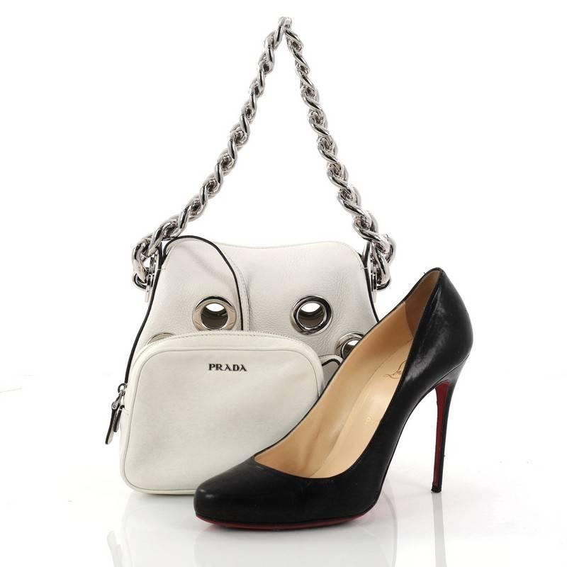 This authentic Prada Grommet Chain Hobo Vitello Daino Small is a gorgeous shoulder bag perfect for your day or evening looks. Crafted from white vitello daino leather, this chic bag features chunky silver chain shoulder strap, large grommets