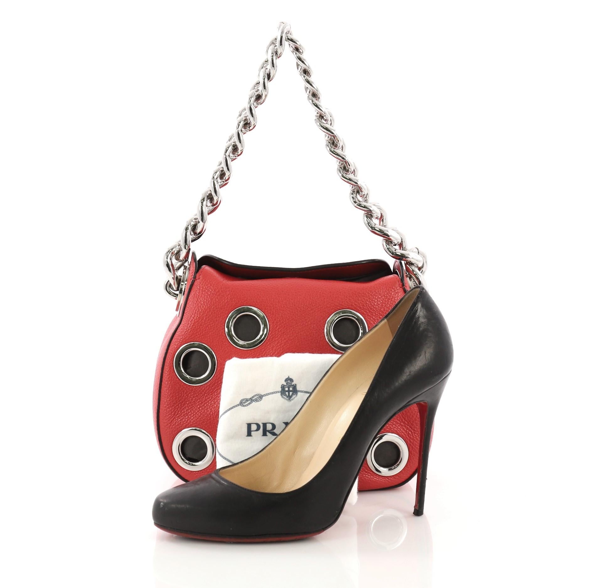 This Prada Grommet Chain Hobo Vitello Daino Small, crafted from red vitello daino leather, features a chunky chain shoulder strap, large grommet detailing all throughout, and silver-tone hardware. Its magnetic closure opens to a red leather
