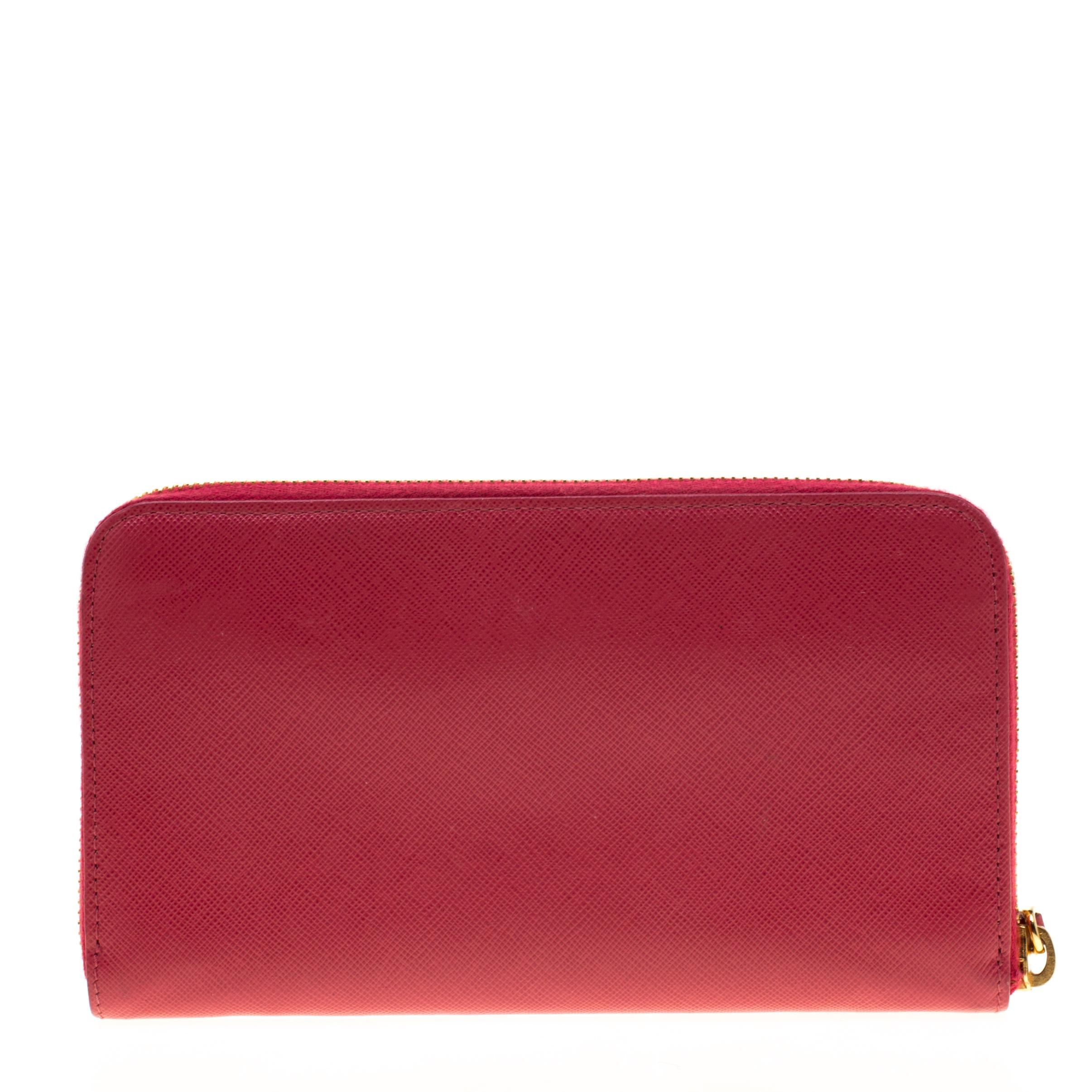 Crafted from hot pink Saffiano leather, this wallet from Prada is sleek and sophisticated. The zip around wallet opens to a nylon-lined interior that houses multiple card slots, two open compartments for currency and bills and one zipped coin