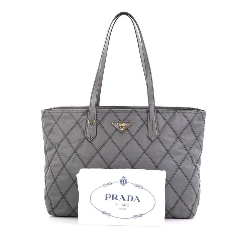 This Prada Impunto Zip Tote Quilted Tessuto Large, crafted in gray tessuto impunto, features dual leather handles, diamond quilted design and gold-tone hardware. Its zip closure opens to a black fabric interior with zip and slip pockets.