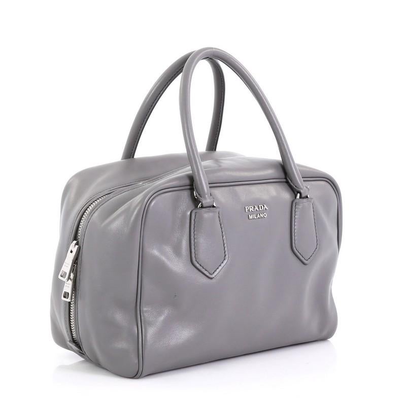 This Prada Inside Bauletto Bag Soft Calfskin Medium, crafted from gray soft calfskin leather, features dual-rolled handles, raised Prada Milano logo, and silver-tone hardware. Its all-around zip closure opens to a green leather interior showcasing