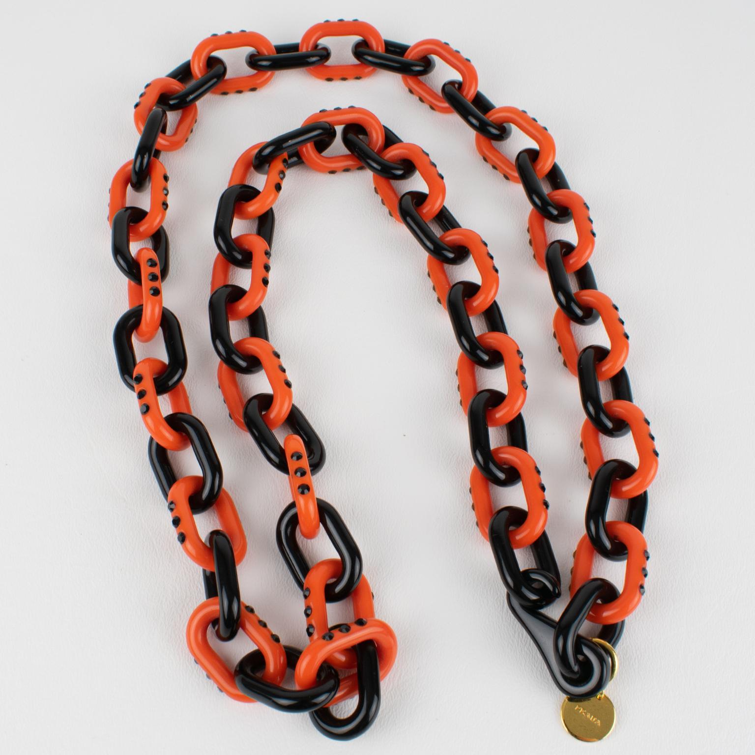 Ce rare collier extra-long de la maison Prada présente une chaîne massive en résine de couleur noire et rouge citrouille avec des strass de cristal de jais noir sertis dans les maillons de la citrouille.
Une étiquette en métal doré arborant le logo