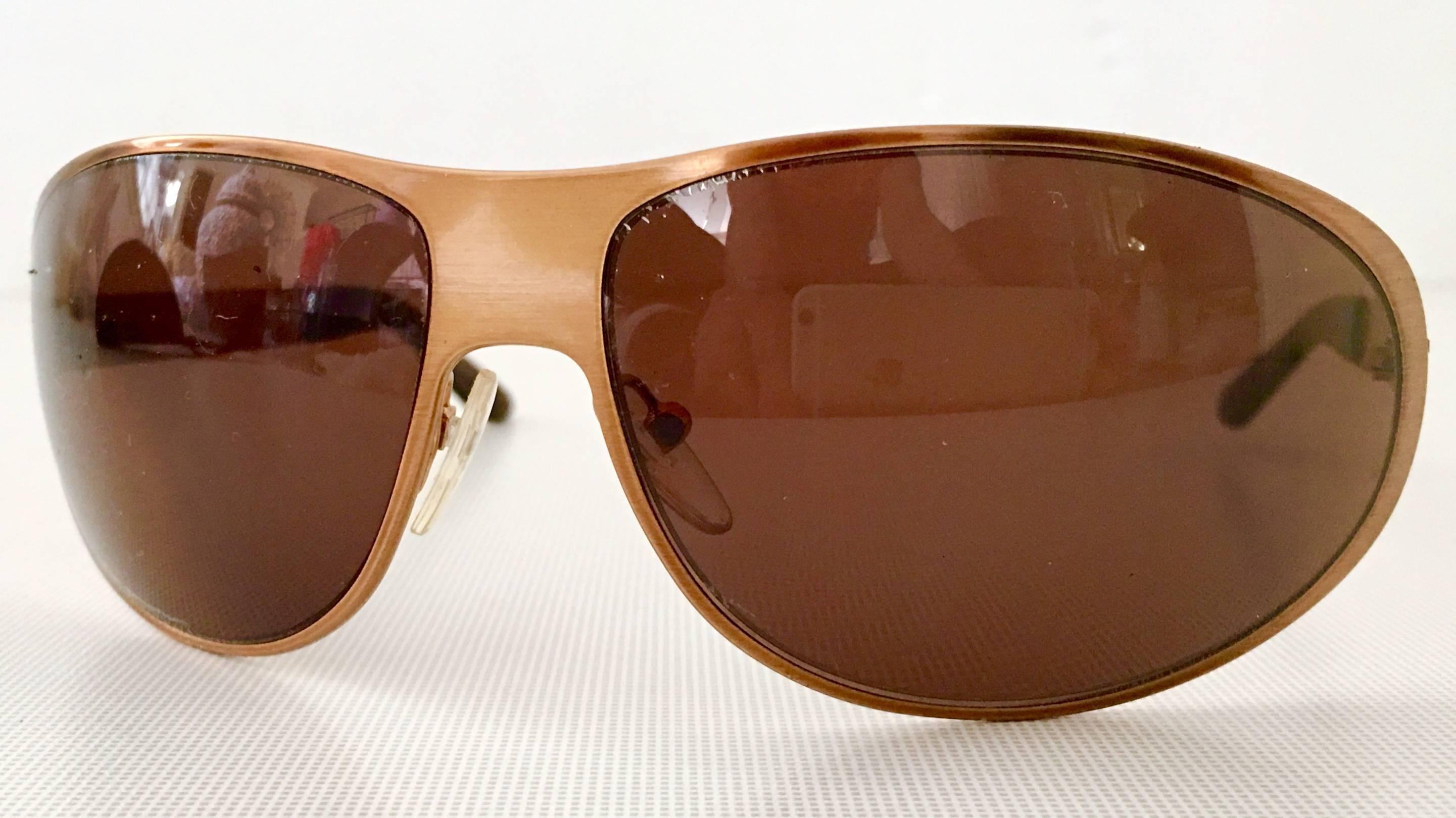 20th Century Prada Rose Gold & Swarovski Crystal Sunglasses, Made In Italy. These sporty but sophisticated sunglasses have a brushed rose gold finish, brown lens and citrine colored Swarovski crystal rhinestone detail. a brown faux tortoise tone
