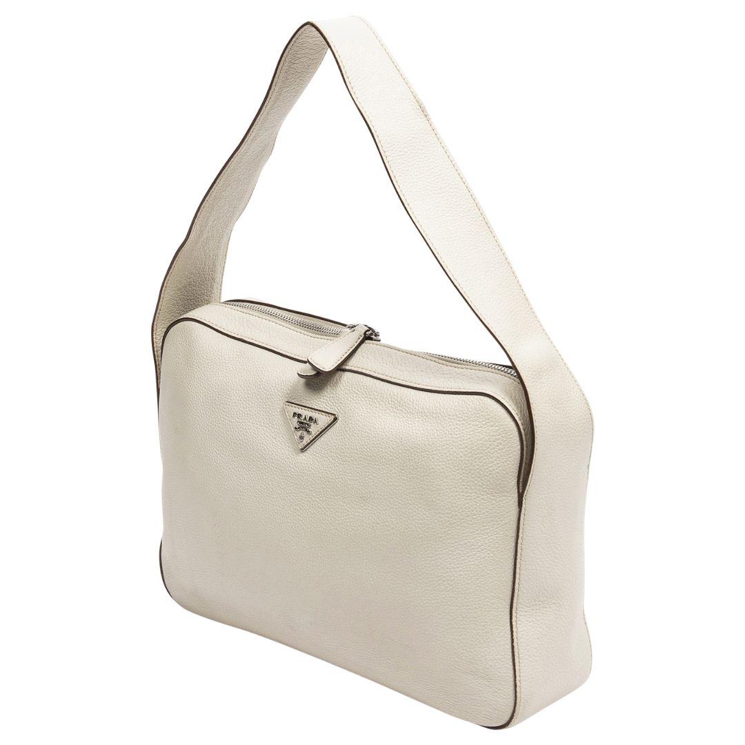 Timeless as can be! Carry her to coffee or wherever your heart desires, crafted in ivory vitello daino leather, silvertone hardware, the fashion house's signature logo to the front, and a single flat shoulder strap. The zipper closure opens to a
