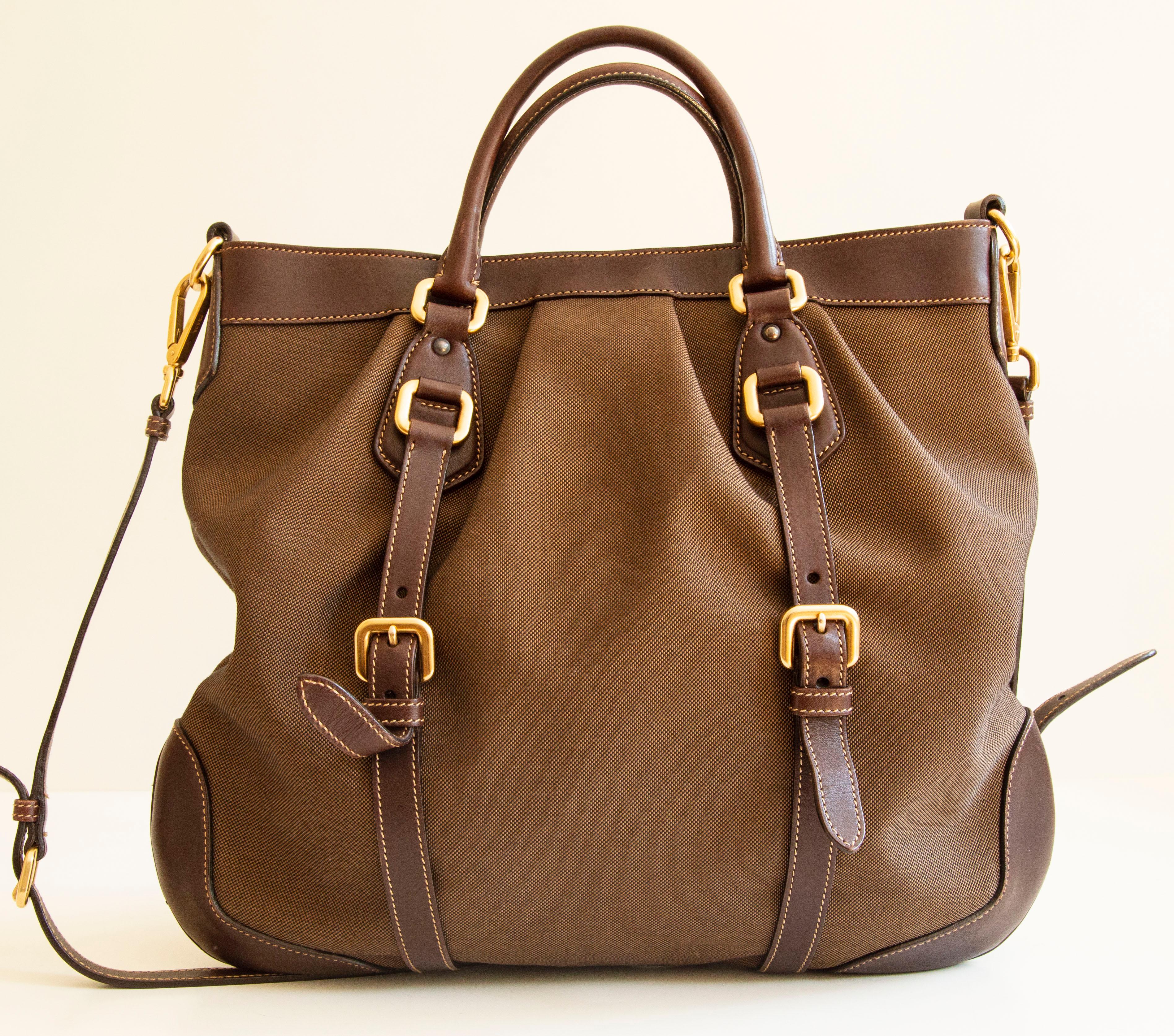 Un authentique sac en Jacquard à double sens de Prada. Le sac se compose d'une toile Jacquard marron, d'une garniture en cuir marron et d'une quincaillerie dorée. L'intérieur est doublé de tissu synthétique Prada et comporte une poche latérale