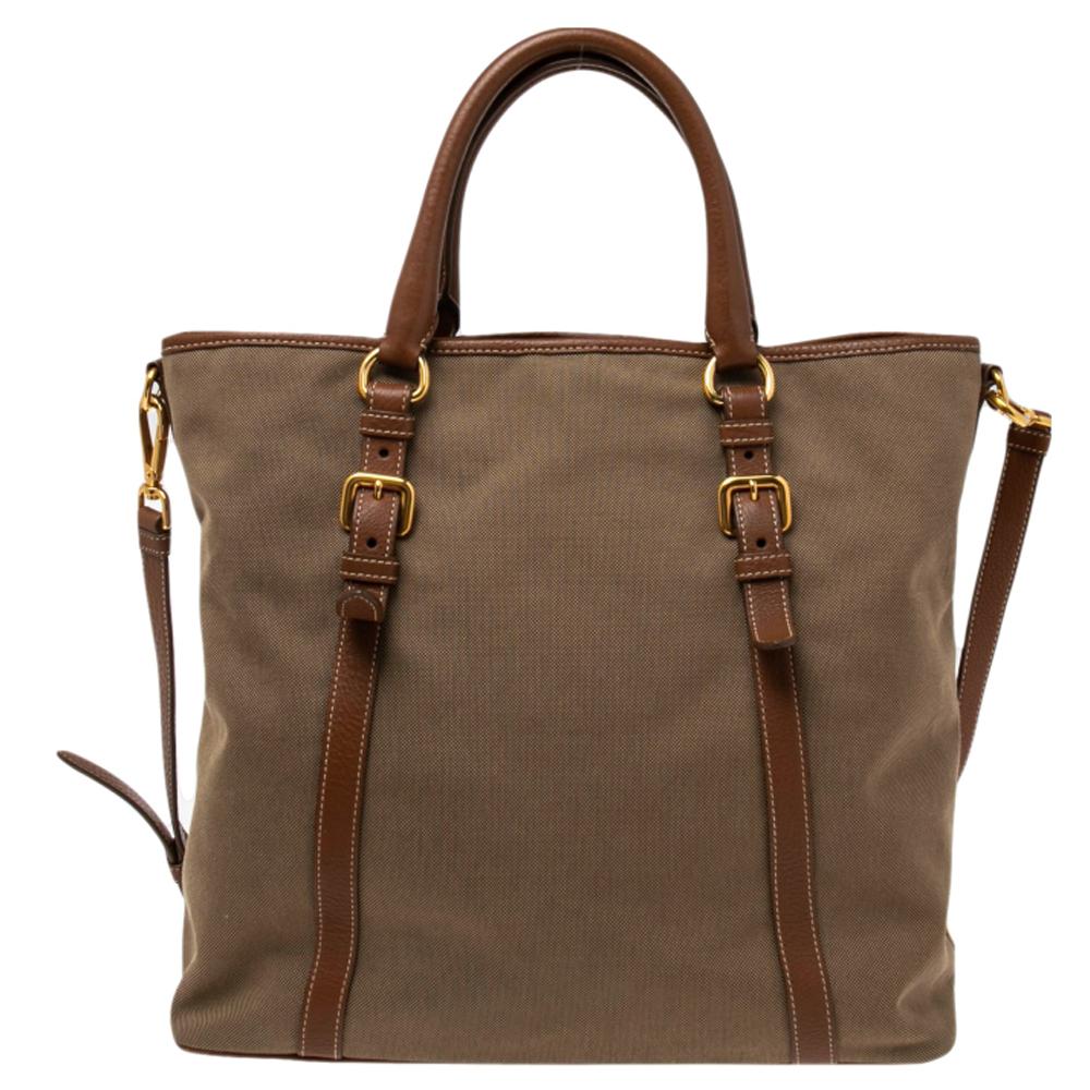 Designed to deliver style and functionality, this tote bag by Prada has been crafted from canvas and leather. It features dual handles, a shoulder strap, a spacious nylon interior, gold-tone hardware, and logo detailing. It is great for everyday