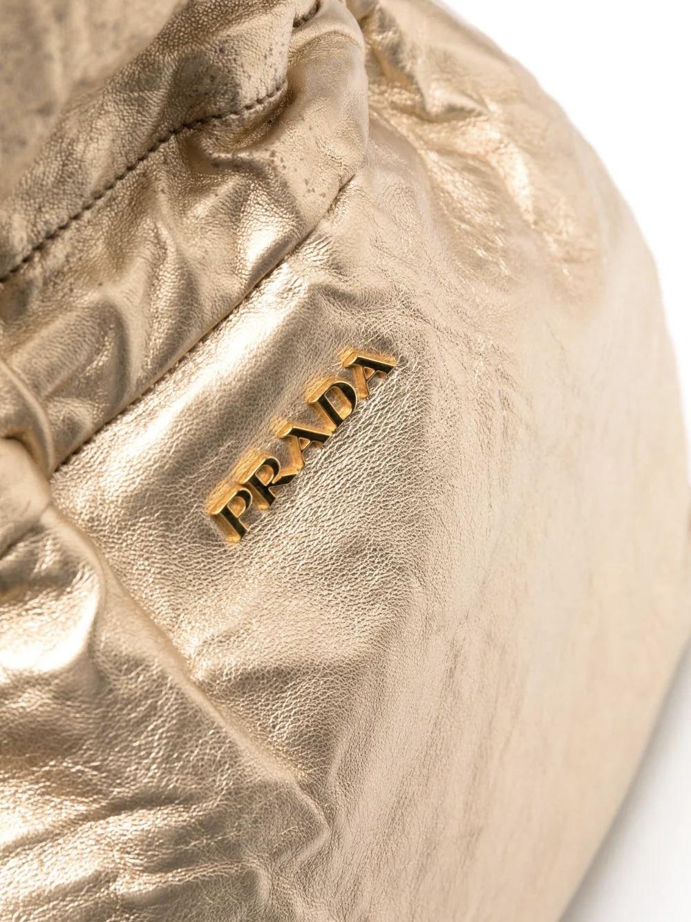 Prada gold-tone large leather tote bag featuring a front logo, natural handles and natural drawstring fastening, a soft lamb leather foiled finish, a magnetic fastening, inside usual Prada monogram lining. 
100% Leather
In good vintage condition.