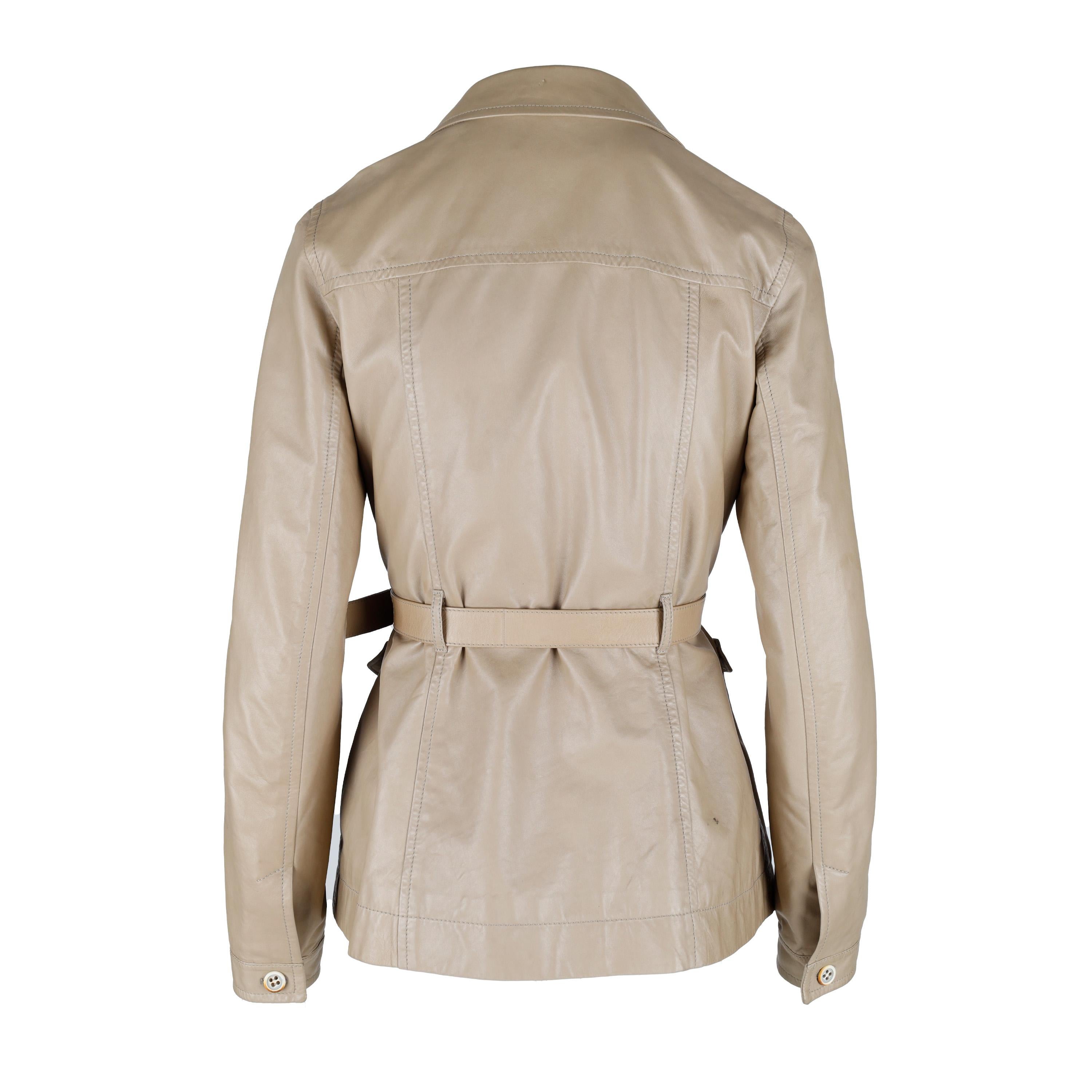 This Prada leather jacket is crafted from soft beige leather for a modern yet classic look. It features a structured silhouette with front pockets and lapel collar, along with a buckle-adjustable belt for added shaping. Perfect for any