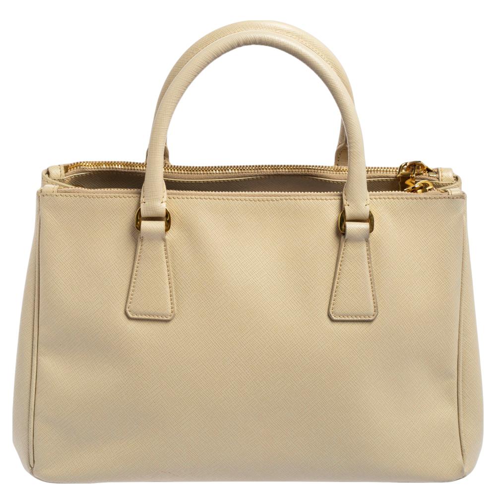 Feminine in shape and grand on design, this Double Zip tote by Prada will be a loved addition to your closet. It has been crafted from Saffano Lux leather and styled minimally with gold-tone hardware. It comes with two top handles, two zip