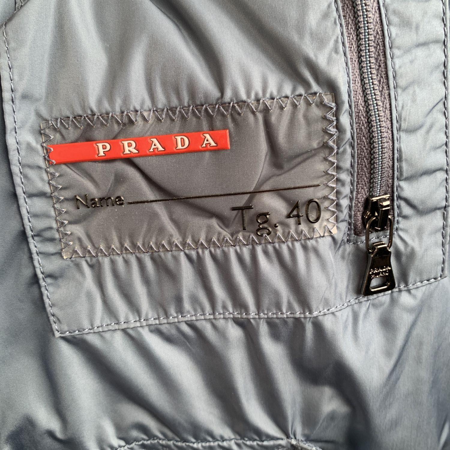 PRADA light blue nylon puffer down jacket, Art. 280721. It features a hooded neckline,  beaver fur trim on the hood, down feathers filling, simple quilted shape, zip  closure on the front. 2 zip pockets on the waist and interior pockets.
