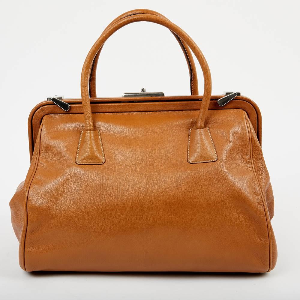 This gorgeous Prada bag is crafted from brown leather and features two rolled top handles. I very good condition with a sign of wear on the right corner (see last picture).
It has a doctor's bag shape and silver-tone hardware. The interior is fabric