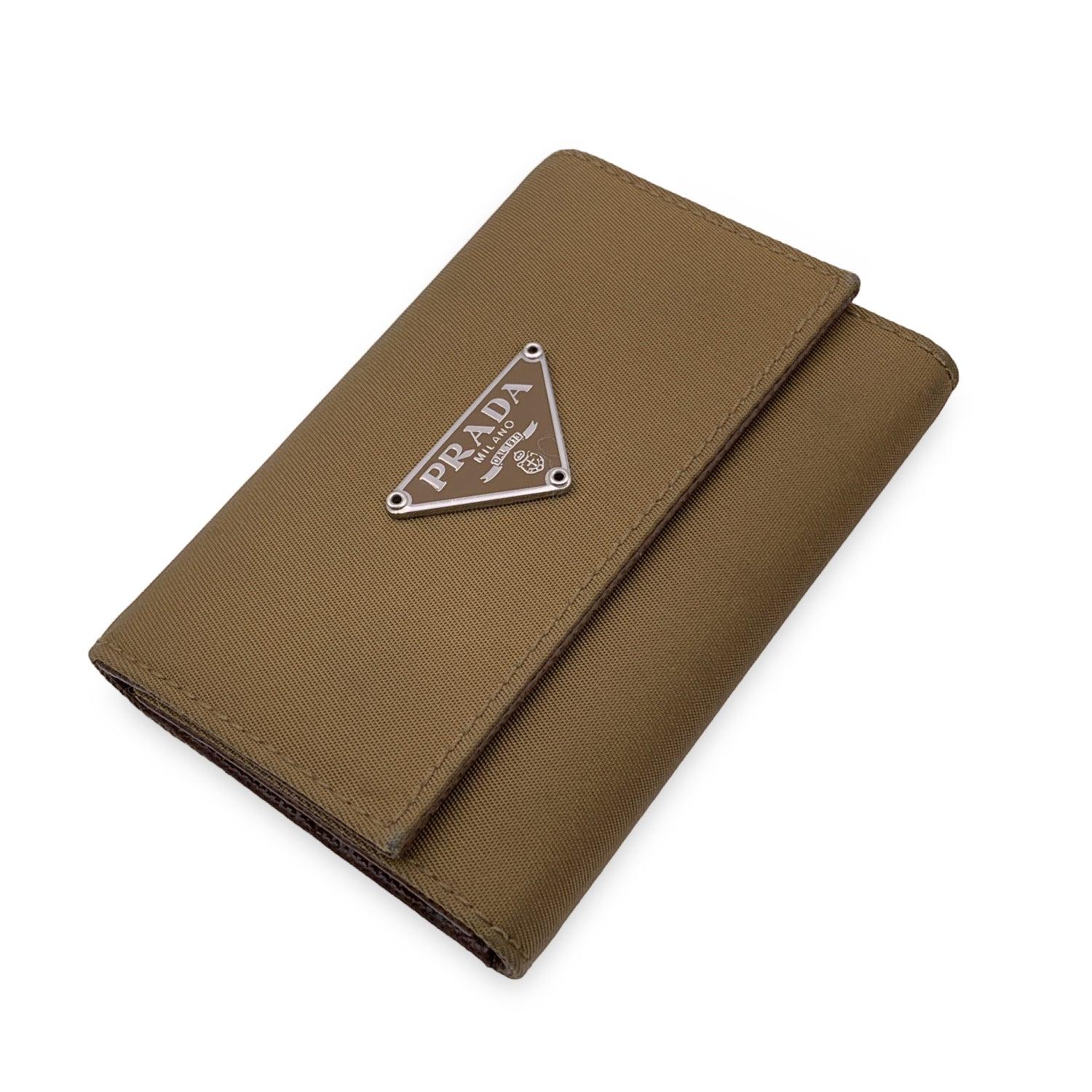 Key case in light brown nylon canvas by Prada. Prada triangle metal plate on the front. Double snap closure on the front. Leather lining. Silver metal hardware. 6 key rings inside. 'Prada - Made in Italy' embossed inside Details MATERIAL: Canvas