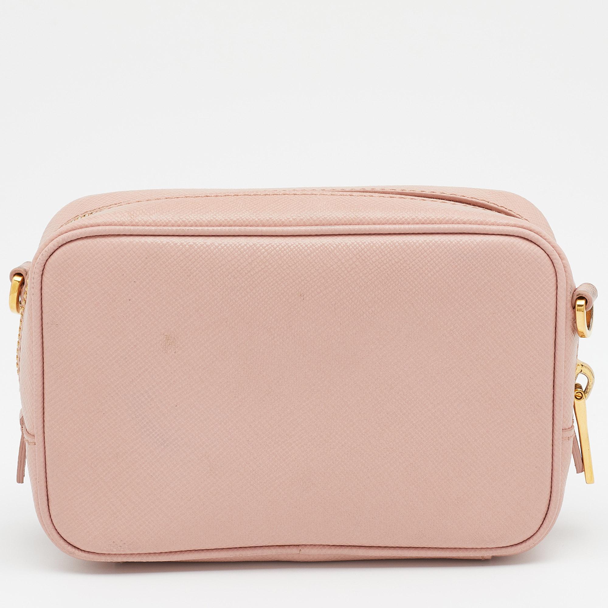 This Prada camera bag is a timeless piece that will last you season after season. This bag is made of light pink Saffiano leather and sized to house your absolute must-haves. It has a long shoulder strap, a lined compartment, front logo detailing,