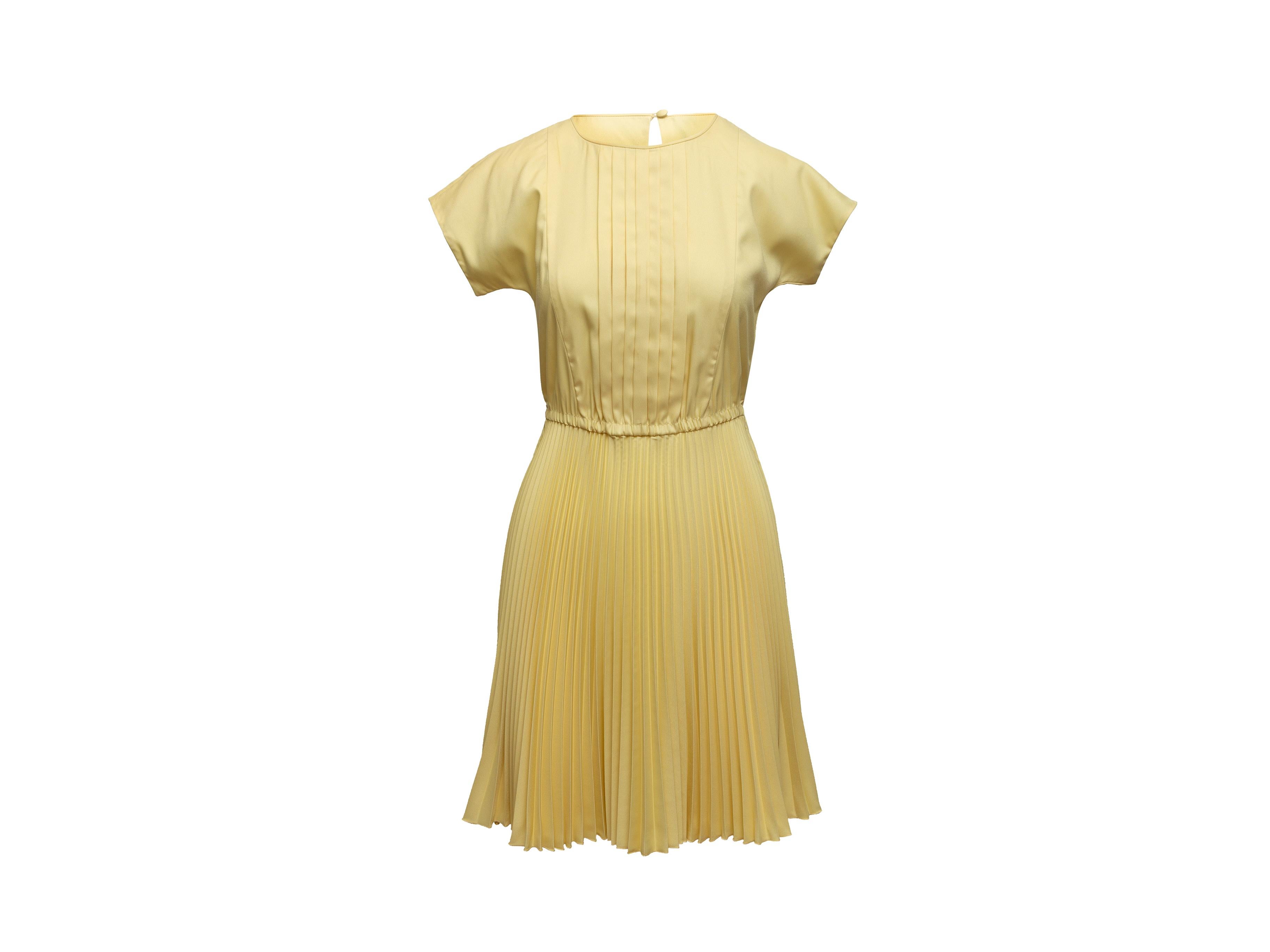 Product details: Light yellow short sleeve pleated dress by Prada. Crew neck. Elasticized waist. Keyhole at nape featuring button closure. 34