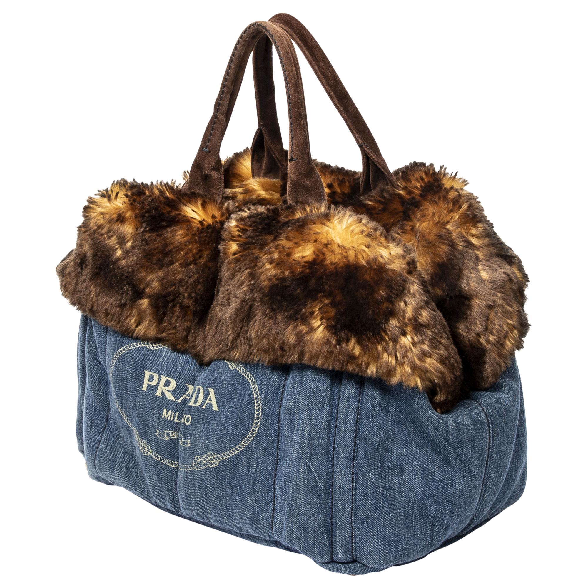 Make a statement with the Prada Limited Edition Large Denim Fur Canapa Tote. Crafted from durable denim in a deep dark blue hue, it's a versatile yet luxurious accessory. Adorned with gold-tone hardware and featuring an open-top design, its logo