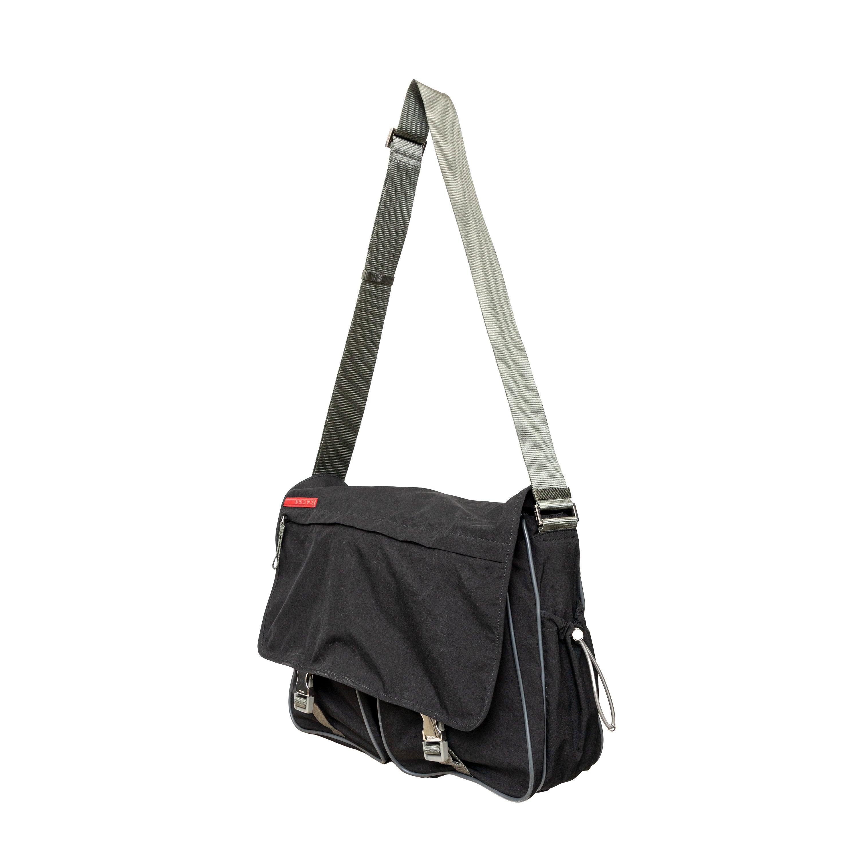 This sporty messenger bag from Prada features silver-tone hardware, an adjustable shoulder strap, three exterior pockets, nylon lining, and dual buckle closure at the front. 
 Measurement: Height:32;Width:38;Depth:10 
 Material: 63% Polyester 37%