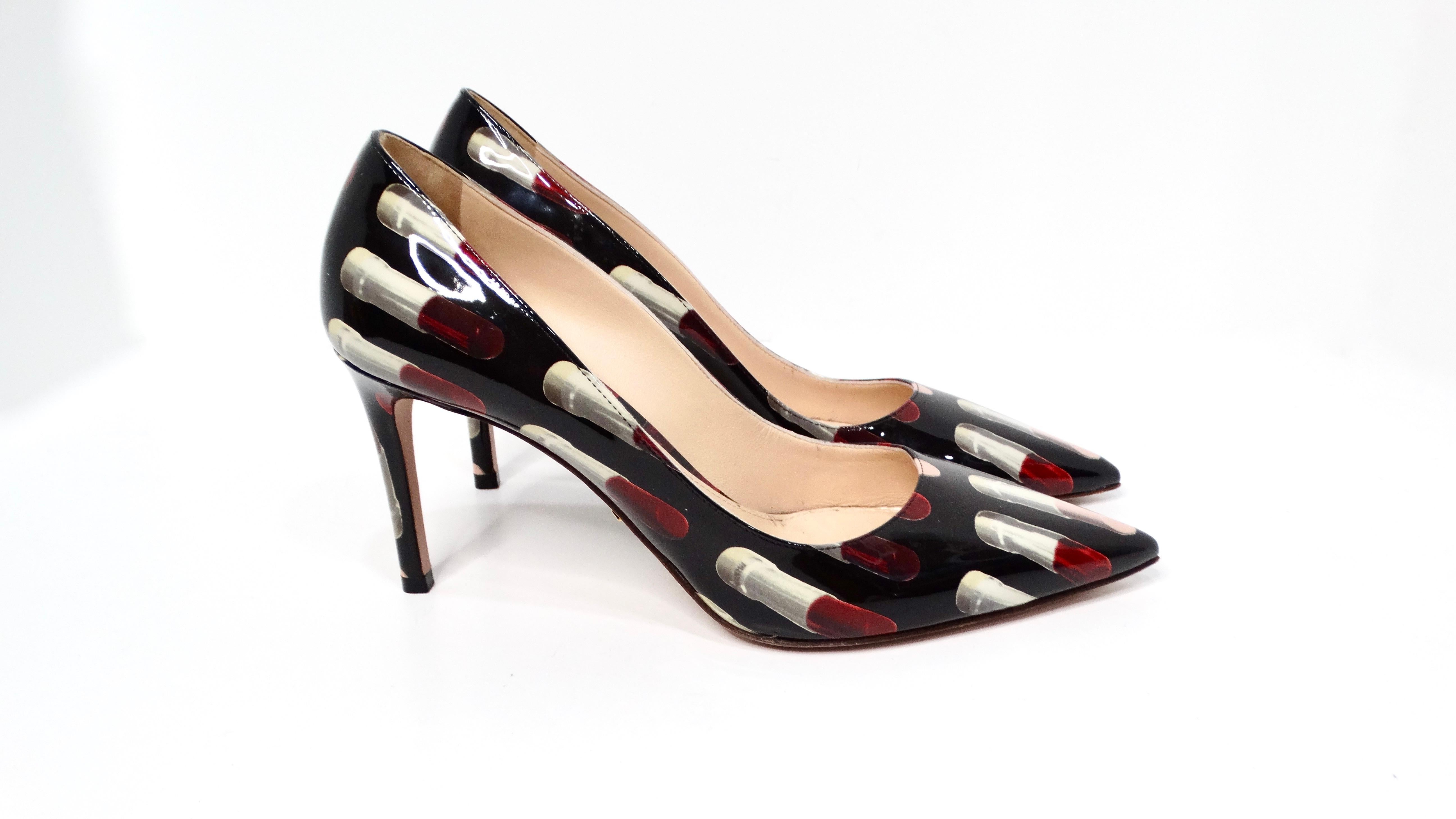 Introducing the Prada Lipstick Print Patent Leather Pumps, a delightful blend of whimsy and sophistication that will invigorate your footwear collection. The sleek black base is adorned with a playful print of vivid red and nude pink lipsticks,