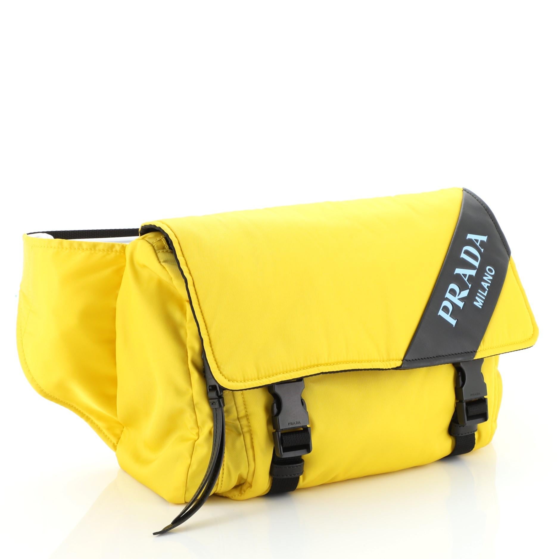This Prada Logo Stripe Messenger Bag Tessuto Medium, crafted from yellow tessuto, features adjustable strap, debossed logo on leather plaque, and black-tone hardware. Its buckle closure opens to a black nylon interior with zip pocket. 

Estimated