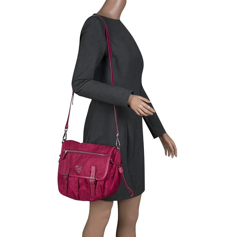 Highly durable for everyday use with an effortless style and luxury, this Prada crossbody bag can fit all that you need through the day. Crafted in magenta nylon material, this bag features a dual silver tone buckle secured front flap closure along